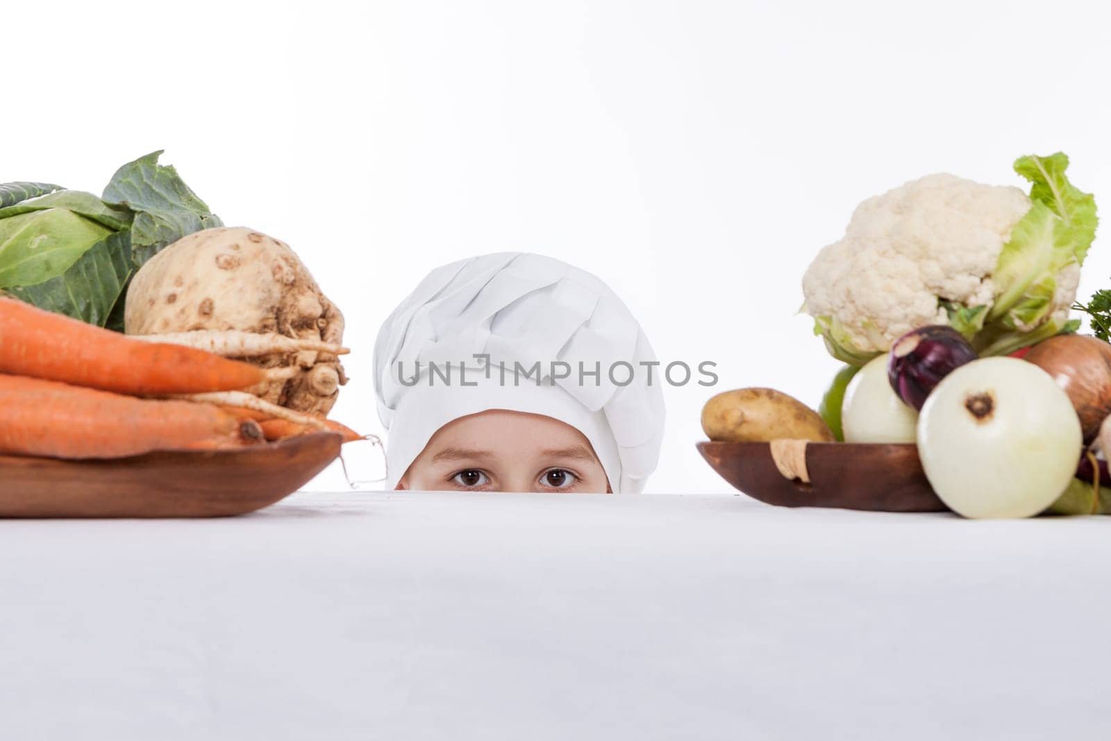 One little boy as chef cook making salad, cooking with vegetables. Isolated on white.
