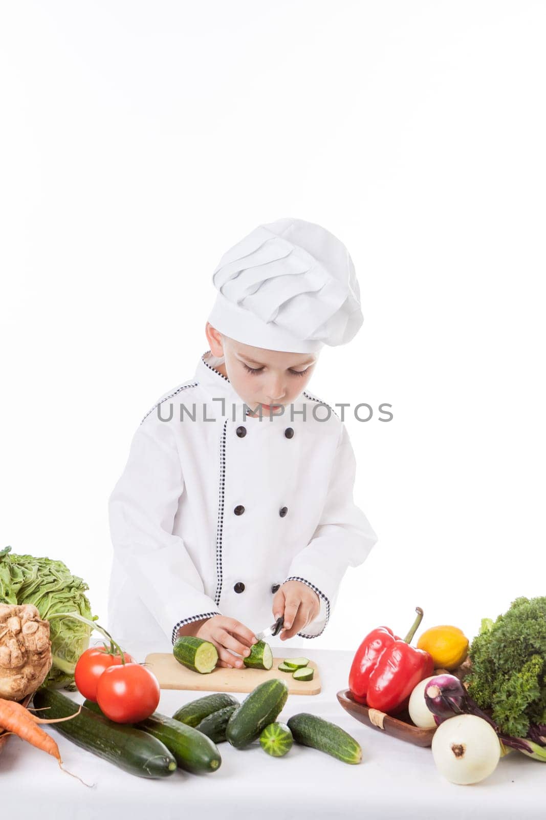 One little boy as chef cook making salad, cooking with vegetables. Isolated on white.