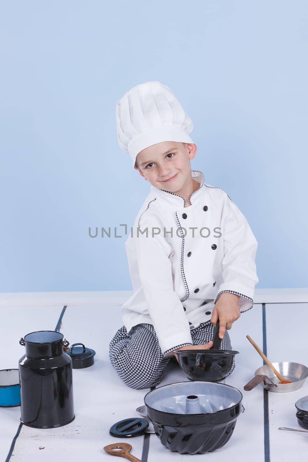 One little boy as chef cook making salad, cooking with vegetables. Isolated on white.