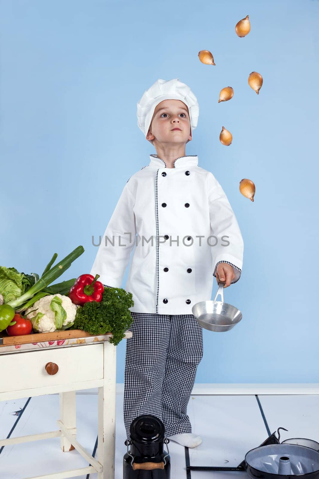 juggling with onions in a pan - One little boy as chef cook making salad, cooking with vegetables. Isolated on white.