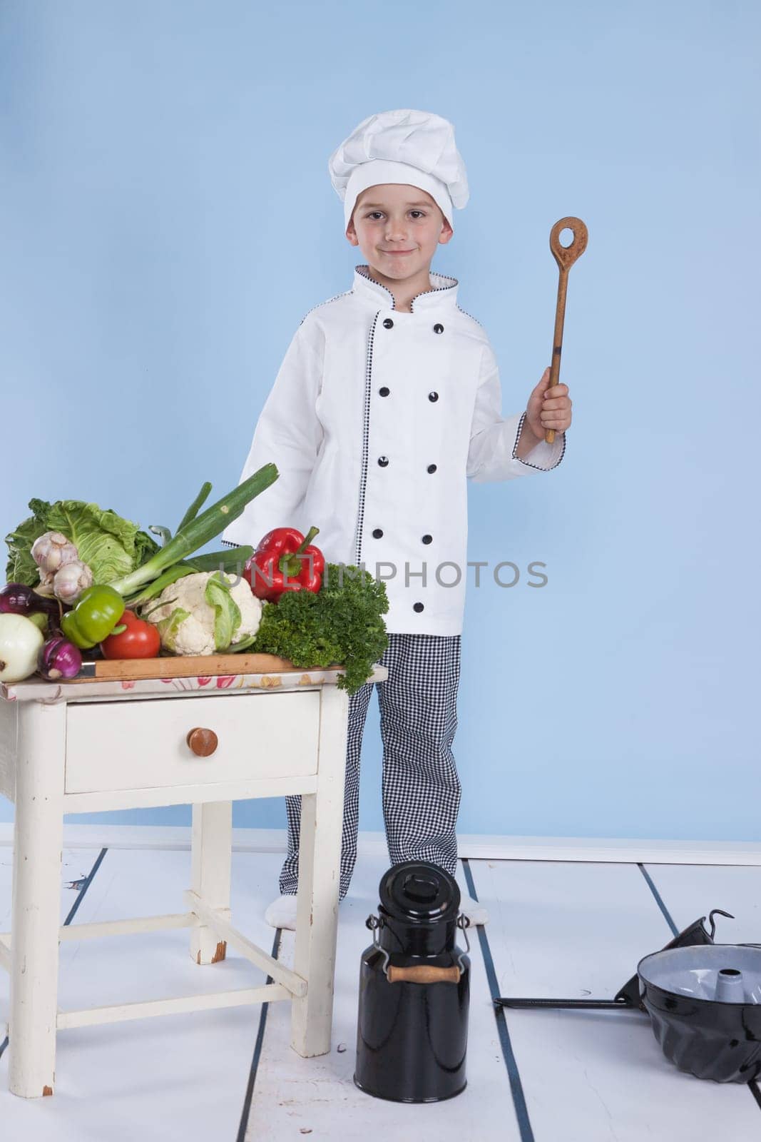 One little boy as chef cook making salad, cooking with vegetables. Isolated on white.