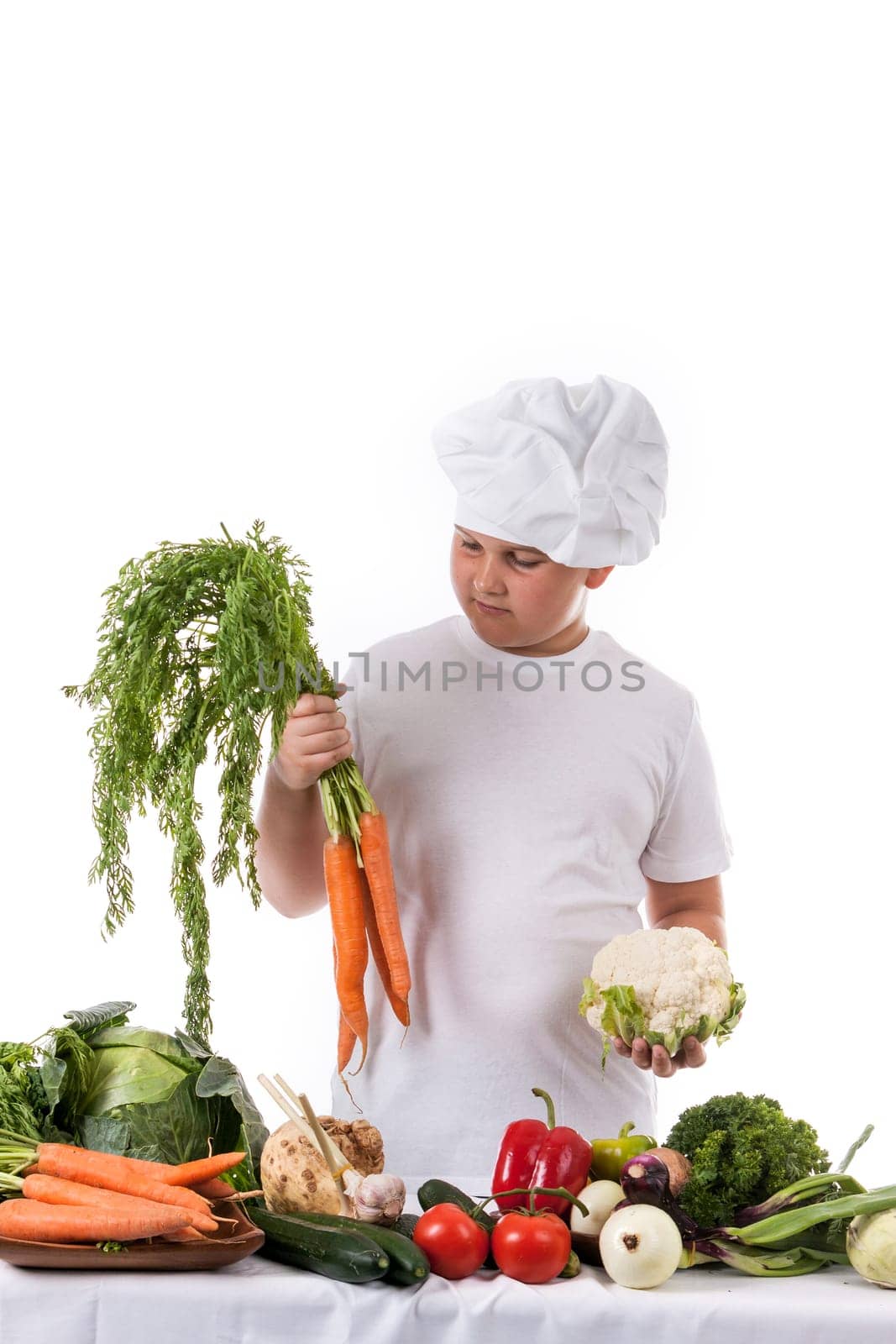 One little boy as chef cook making salad, cooking with vegetables. Isolated on white.
