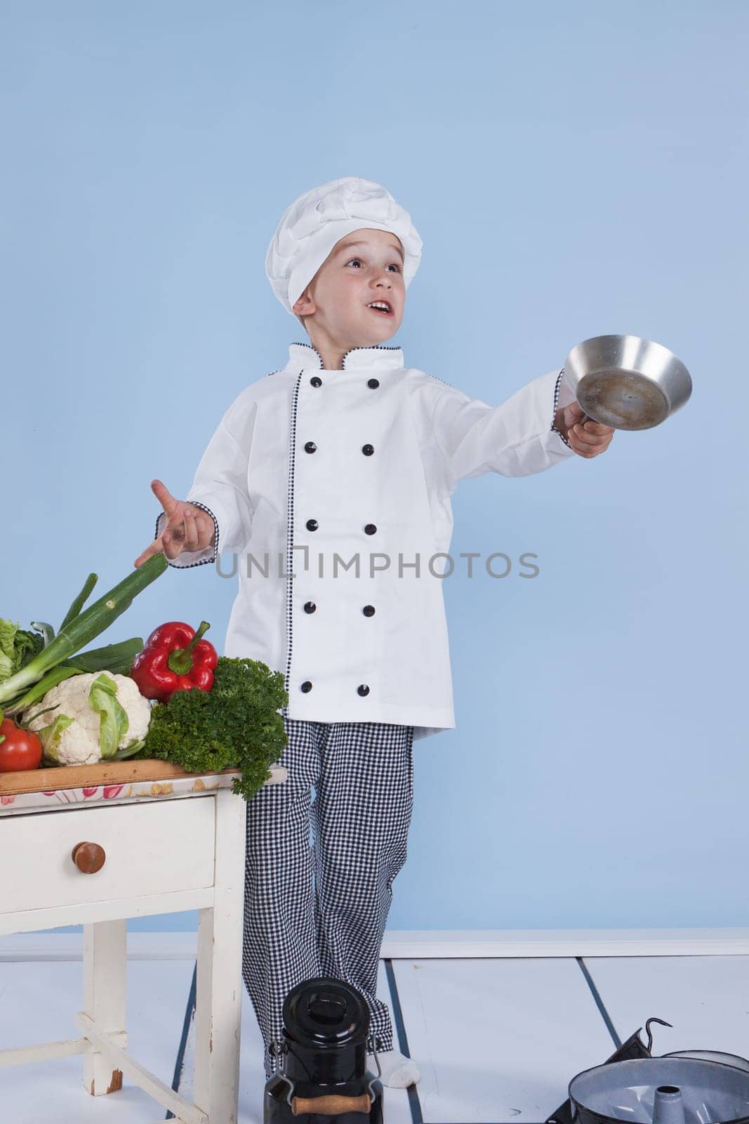 One little boy as chef cook making salad, cooking with vegetables. Isolated on white.