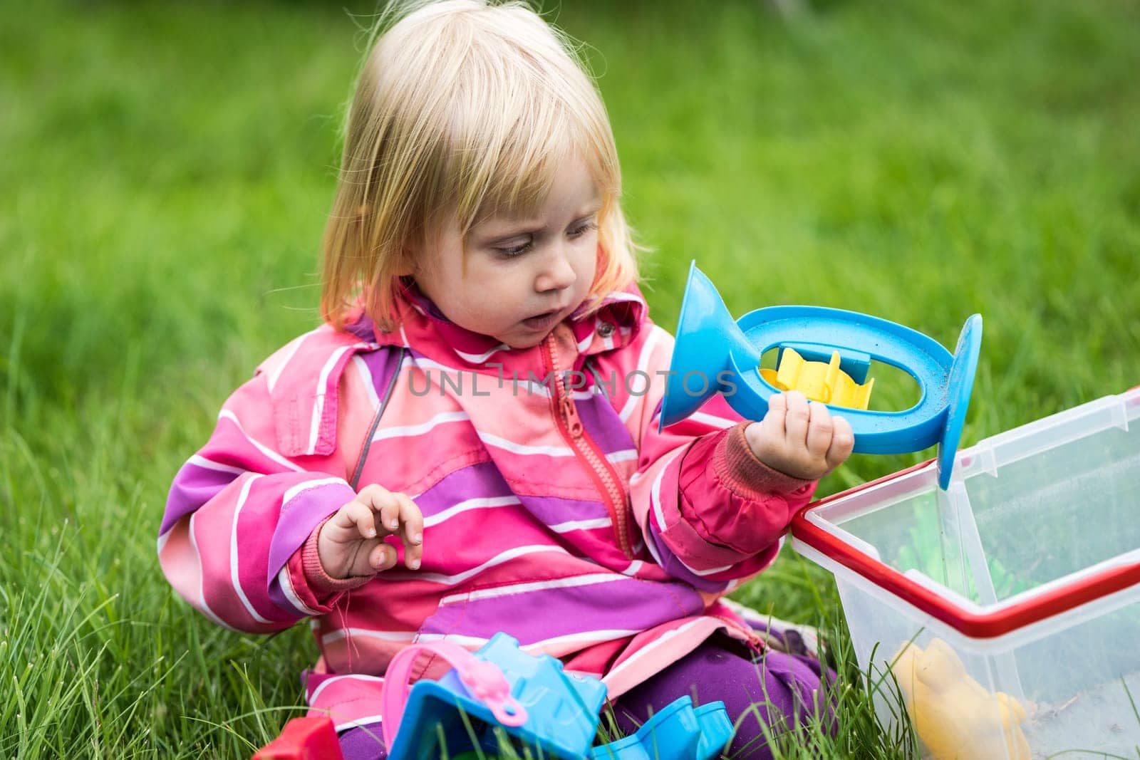 Little girl playing with her toys in the garden