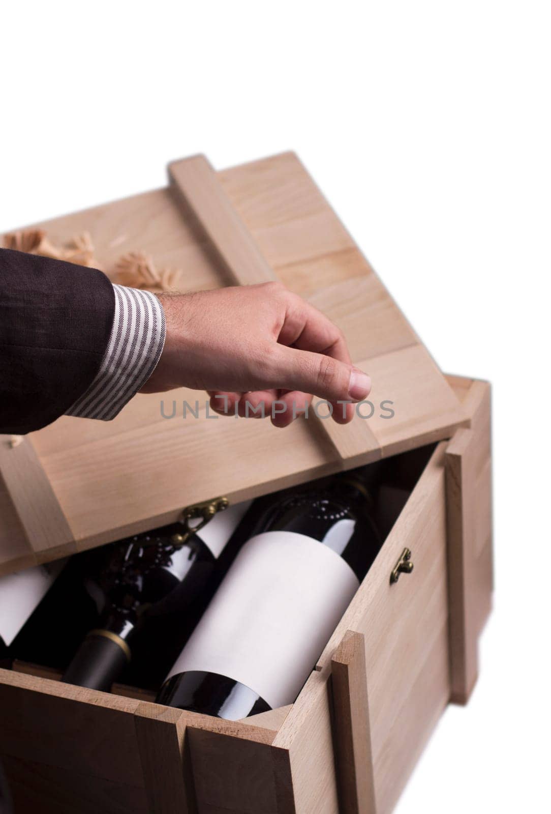 A hand choosing a bottle of wine from a wooden crate