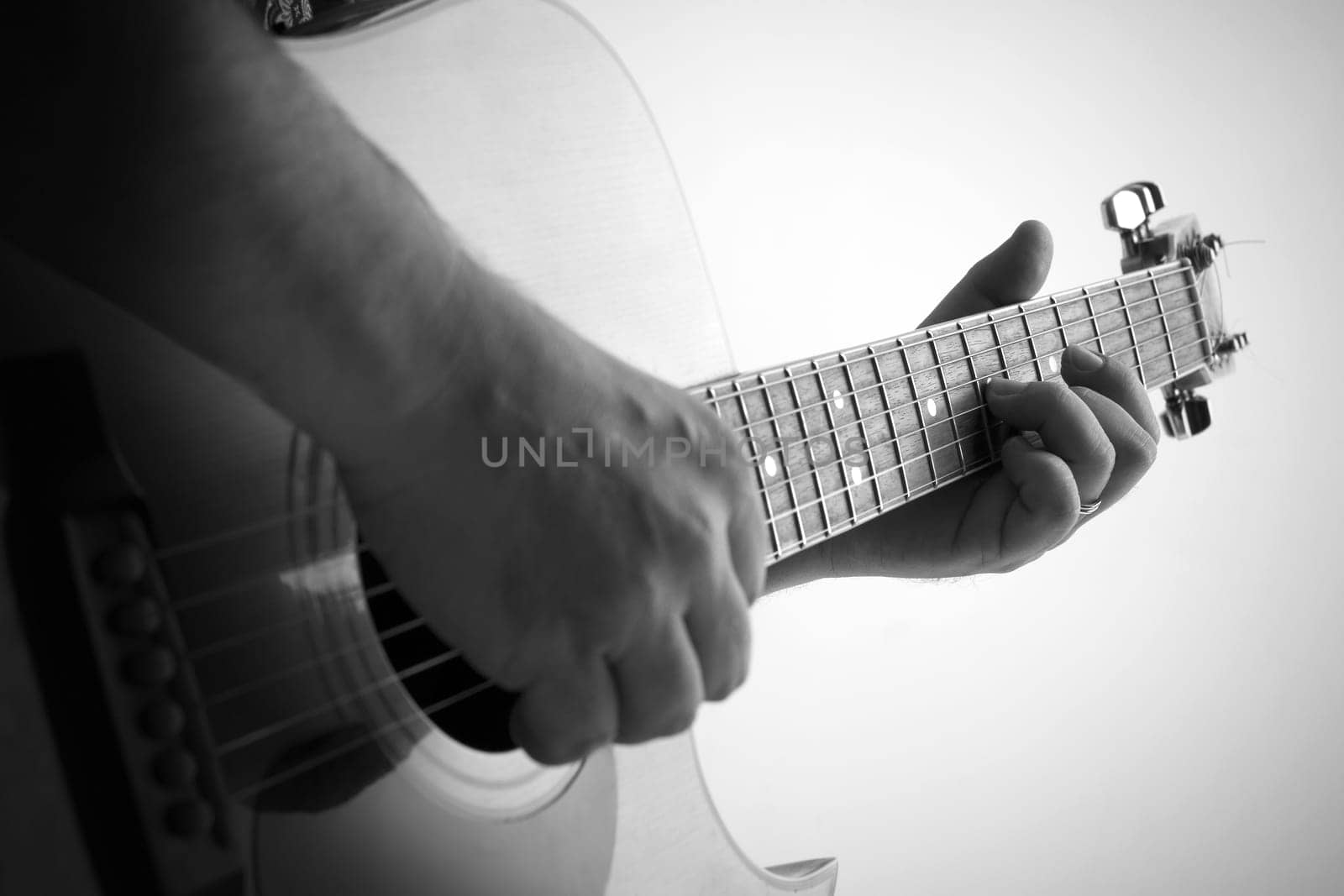 Black and white picture of a man playing the guitar, shallow depth of field