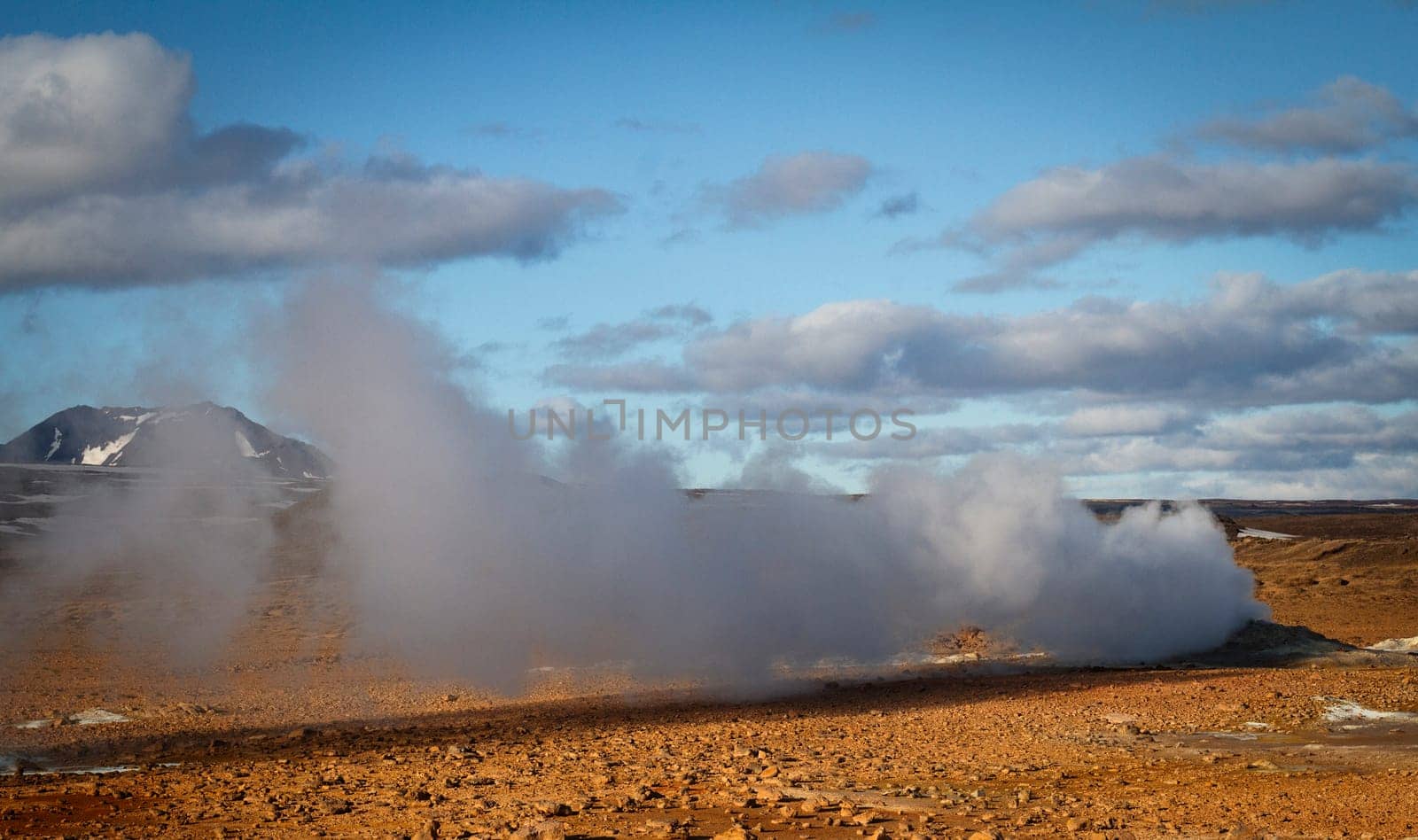Horizontal view of steam hot springs coming out of the ground in the volcanic valley near Myvatn baths in Iceland