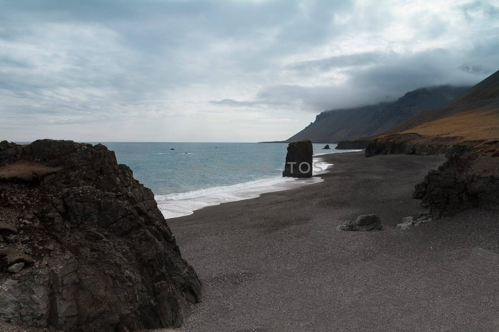 Horizontal view of an Icelandic beach with a huge rock formation in the middle