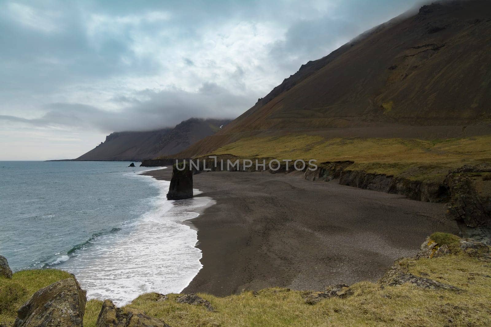 Horizontal view of an Icelandic beach with a huge rock formation in the middle