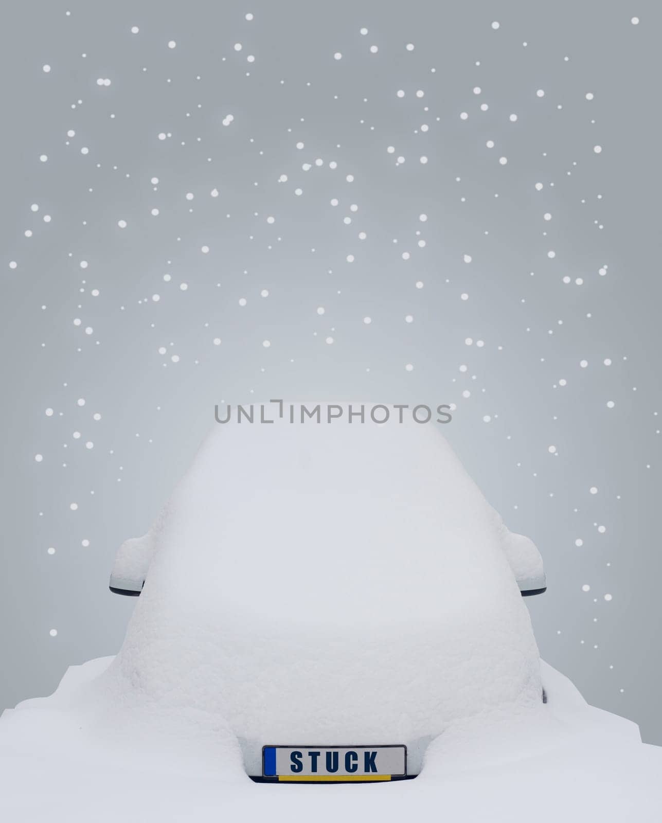 Car covered in snow with the word stuck writen on the license plate and snow flakes falling