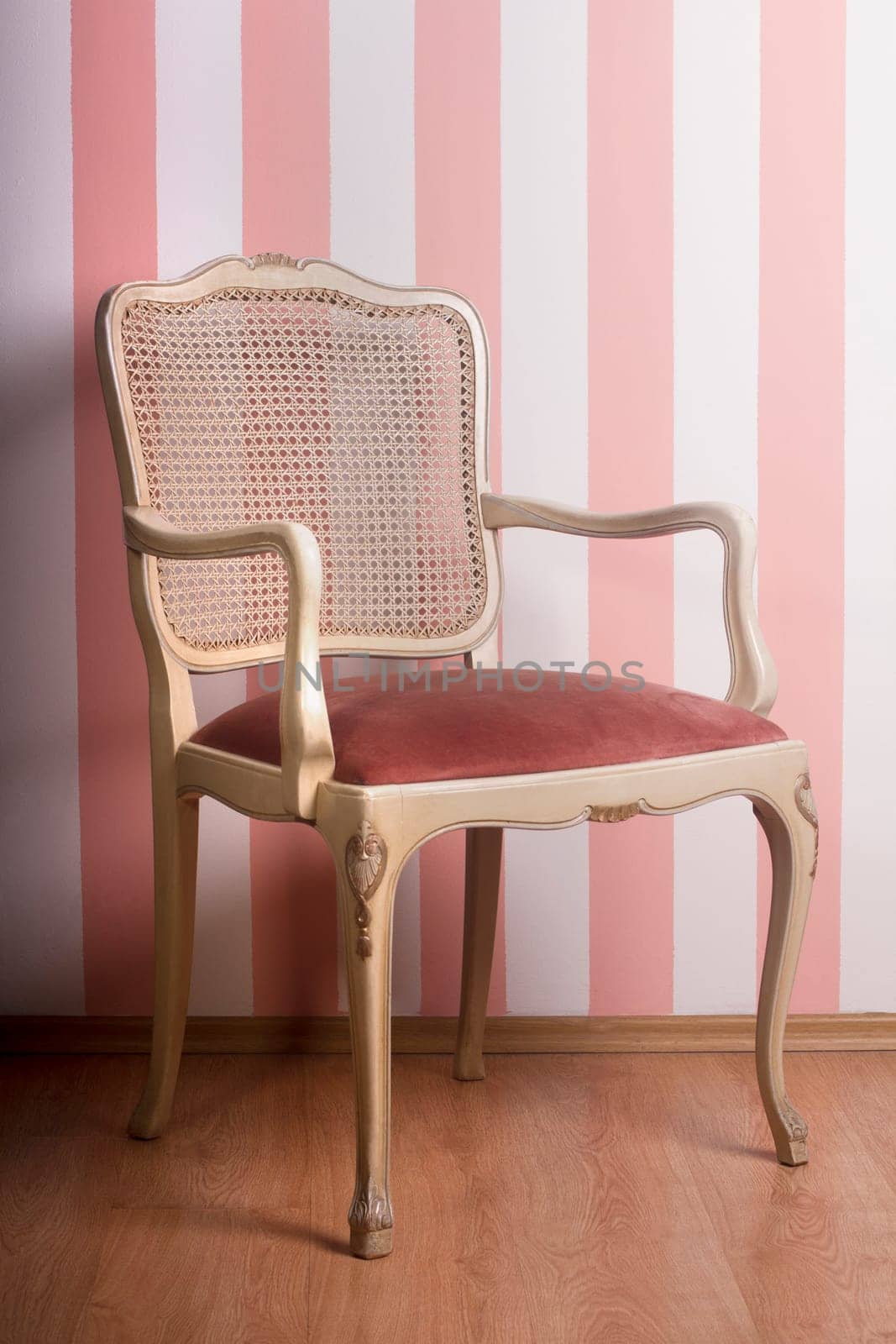Vintage wooden chair against a pink stripe interior wall