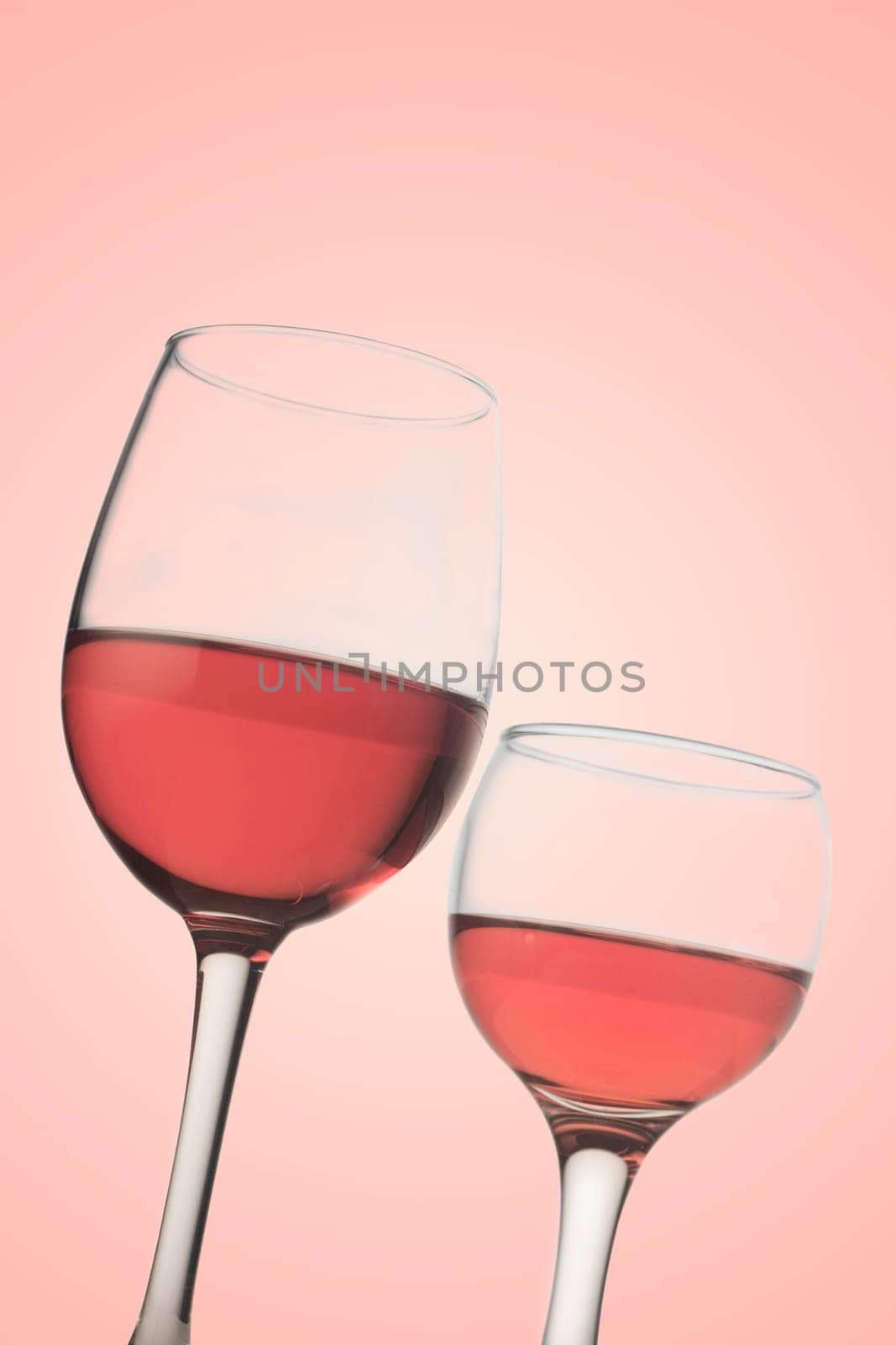 Vertical front view of two rose wine glasses isolated on pink background