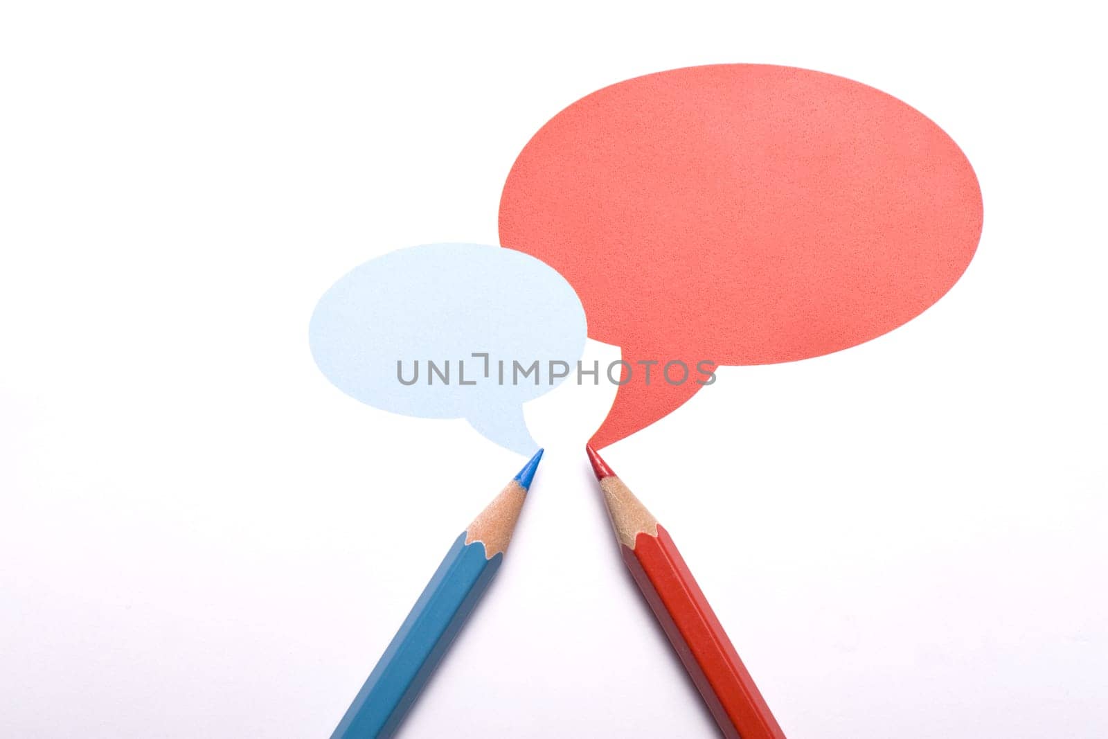 Horizontal top view of a red and a blue pencil with speech bubbles of different sizes above them isolated on white background.