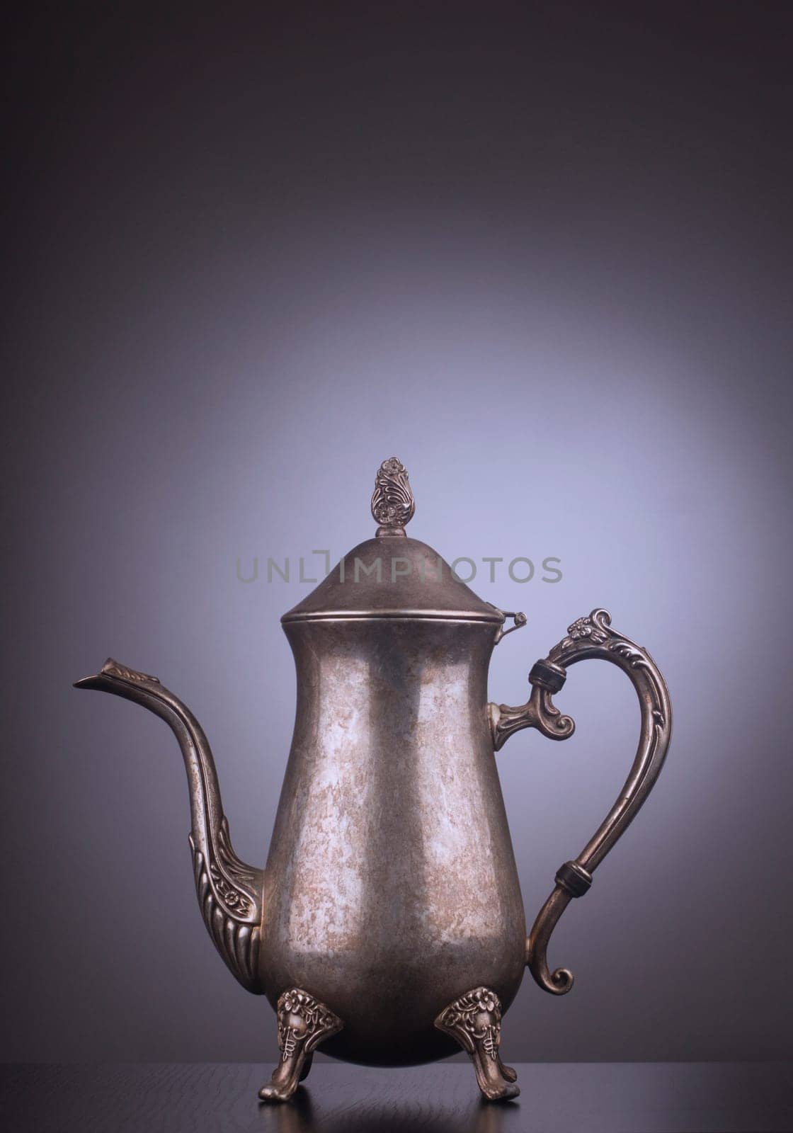 Silver vintage tea kettle with engravings on gray background