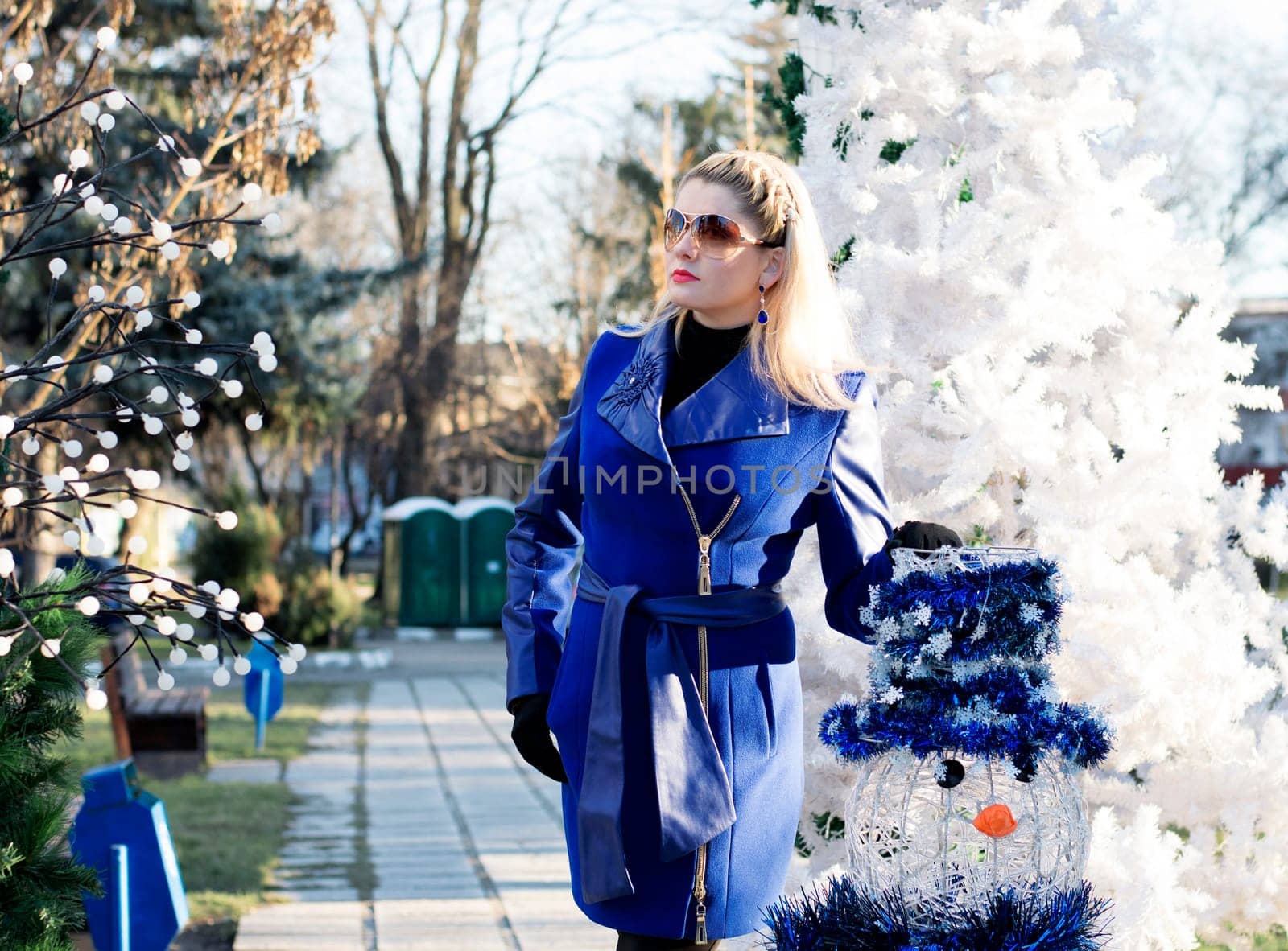 the beautiful woman in a blue coat at a fir-tree and a snowman, a subject the woman and holidays Christmas and New Year