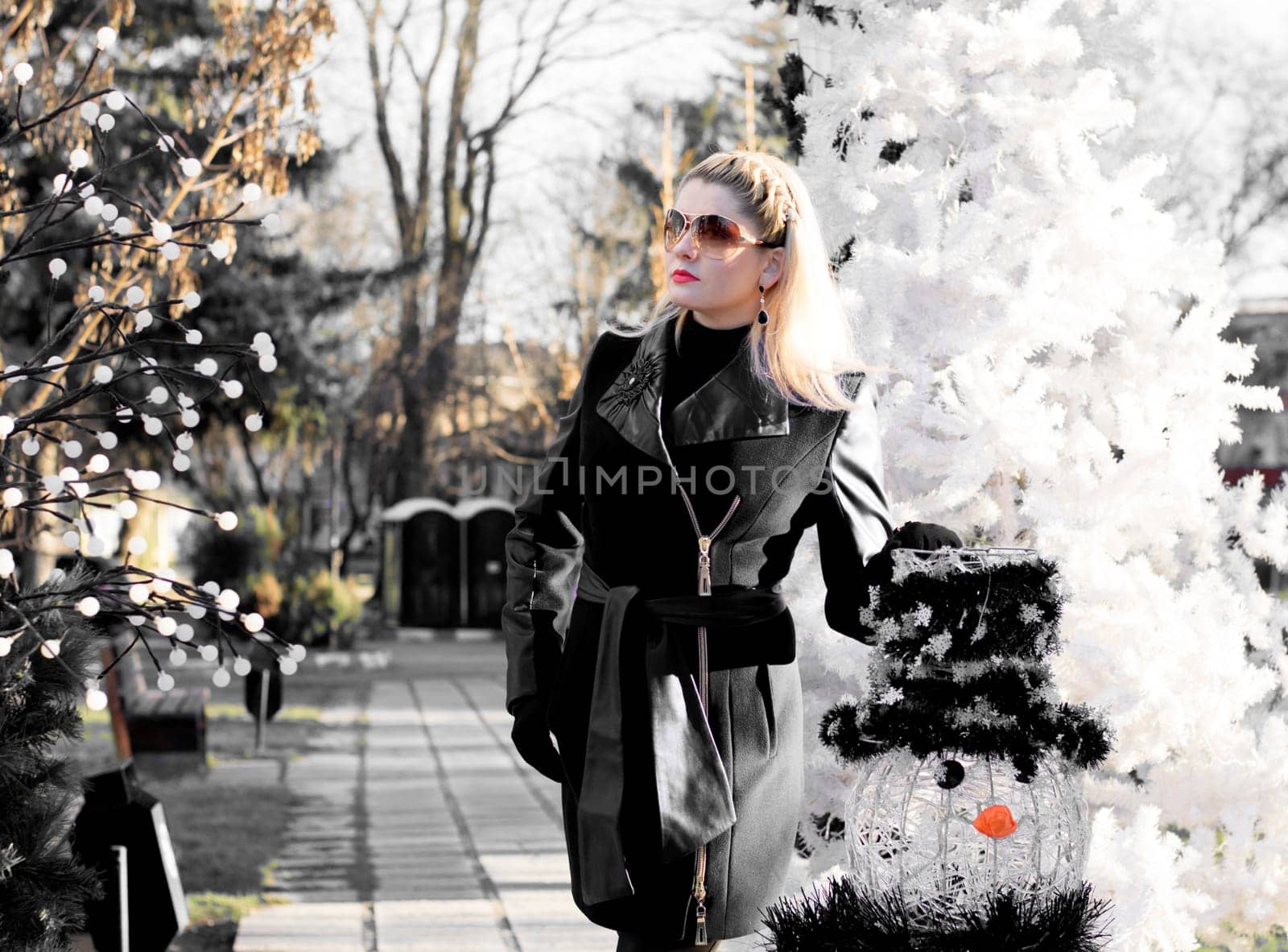 the beautiful woman near a fir-tree and a snowman, the black-and-white photo, a subject of the woman and holidays Christmas and New Year