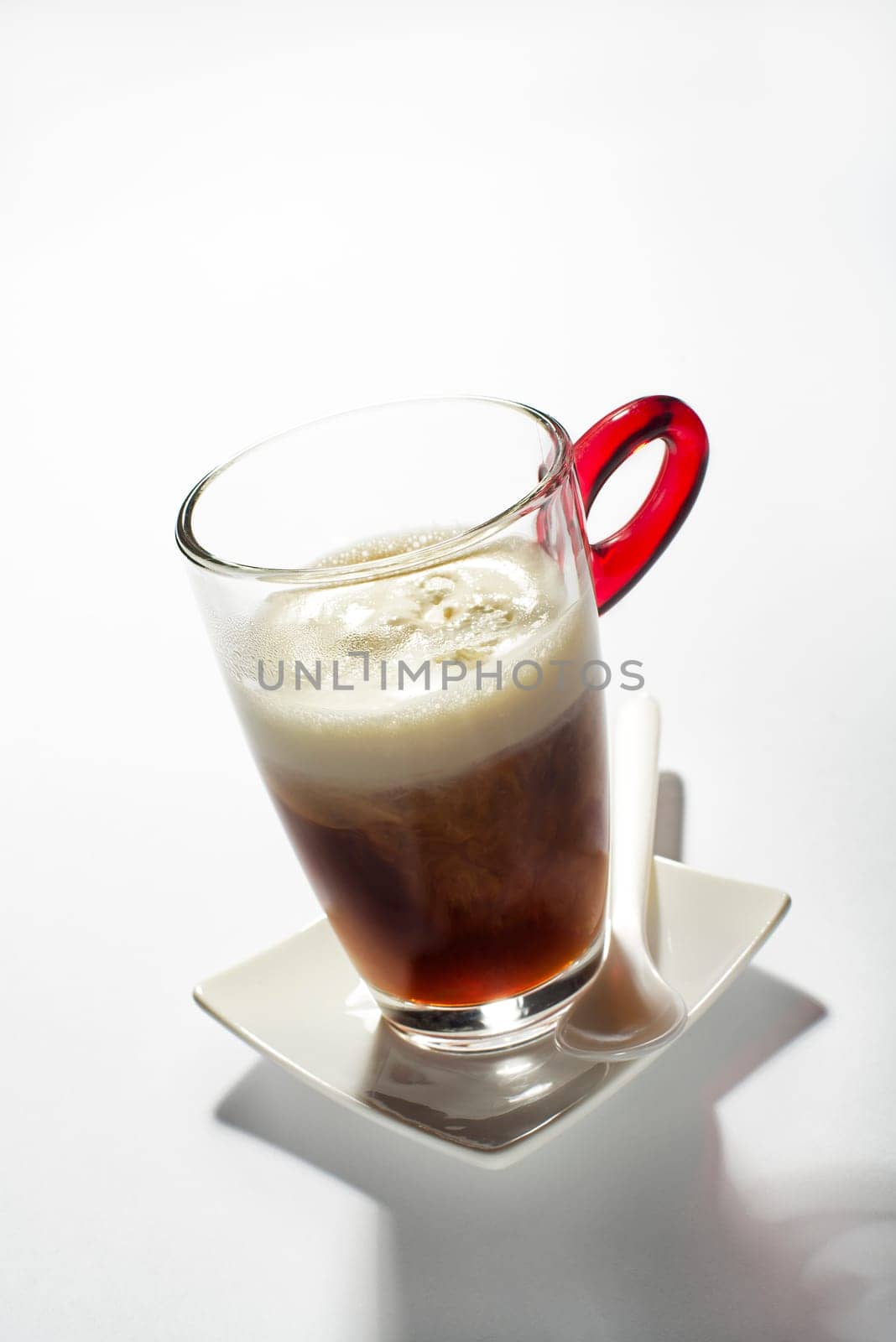 Fresh coffee in a tall glass with cream close up