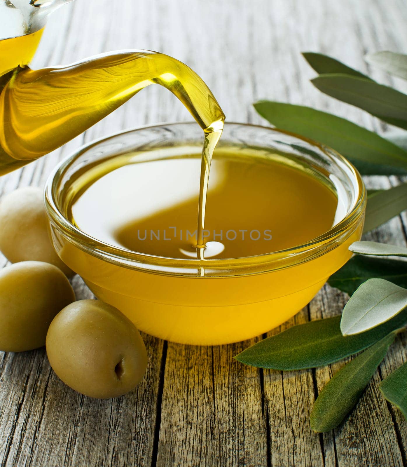 Bottle pouring virgin olive oil in a bowl close up