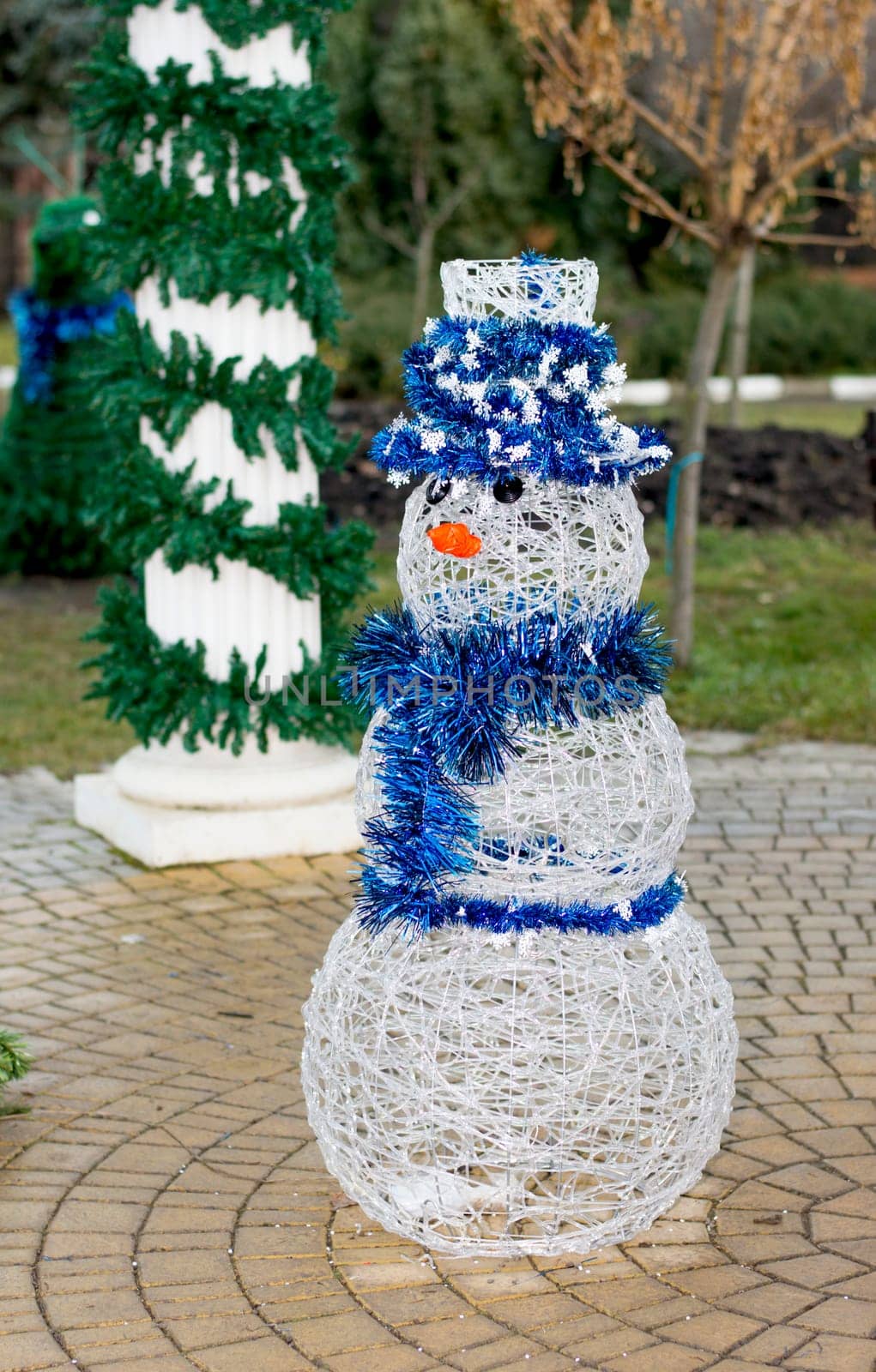 white snowman in a blue hat at the column decorated with a fir-tree, the subject Christmas and New Year