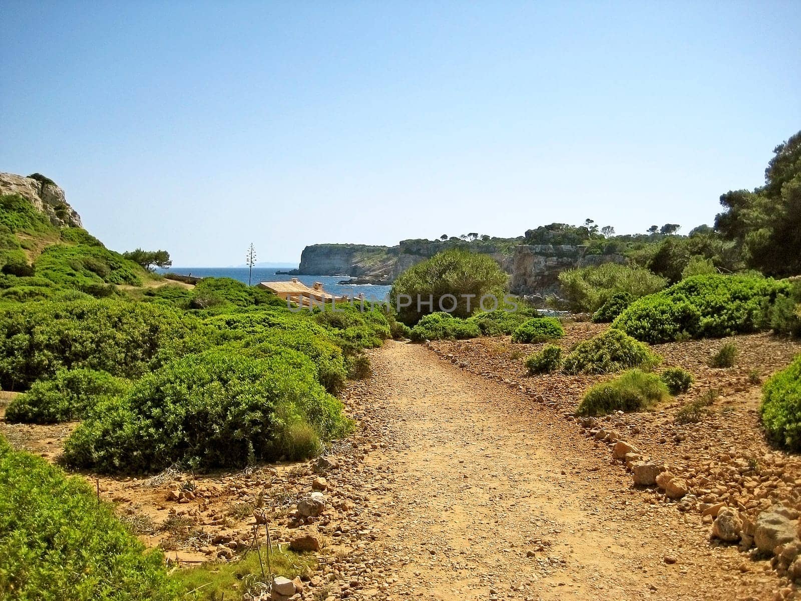 Cliff coast of Majorca in the south-east of the island between Cala s'Almonia and Calo d'Es Moro - stony path in foreground