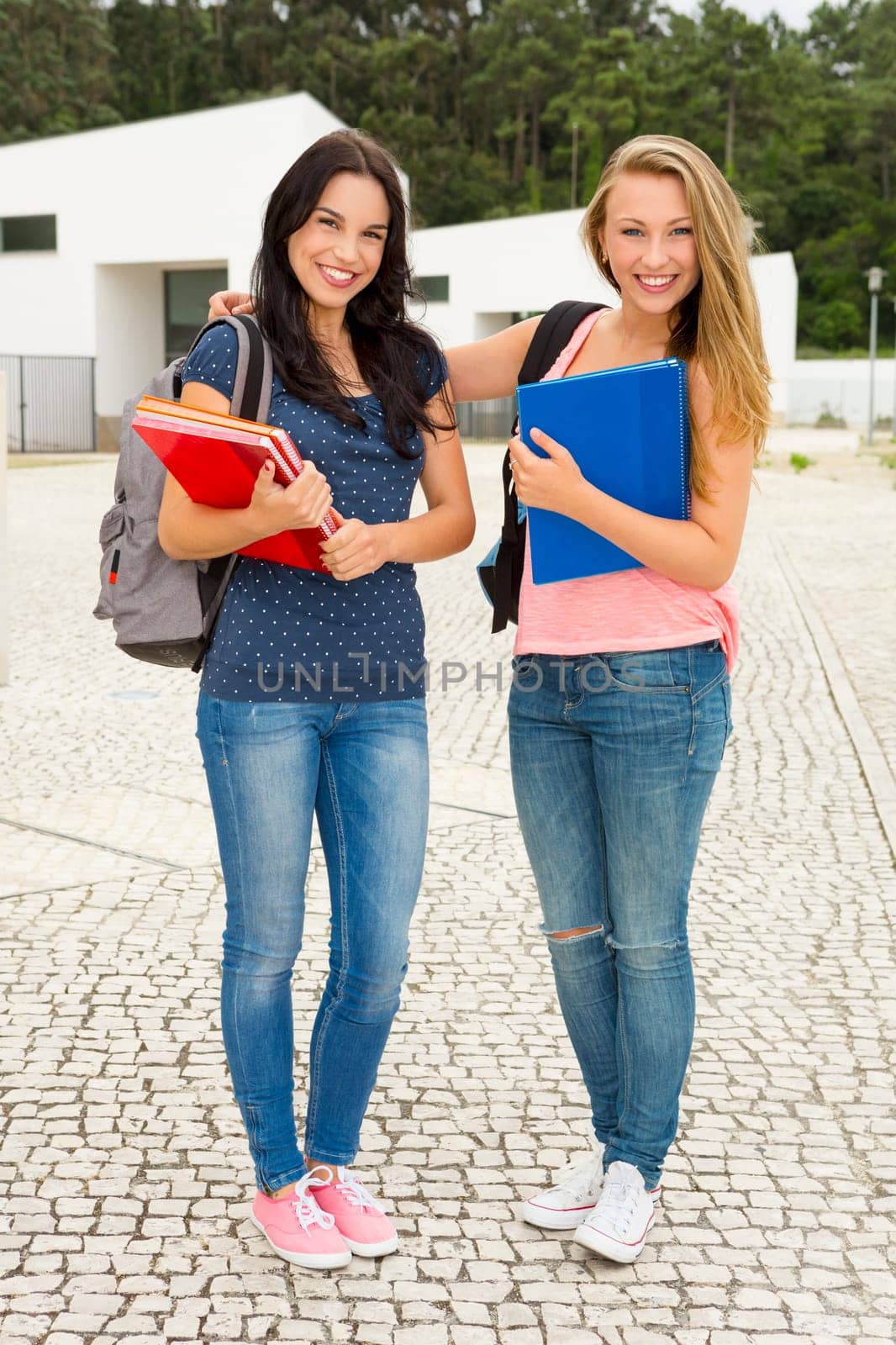 Two happy and beautiful teenage students in the school