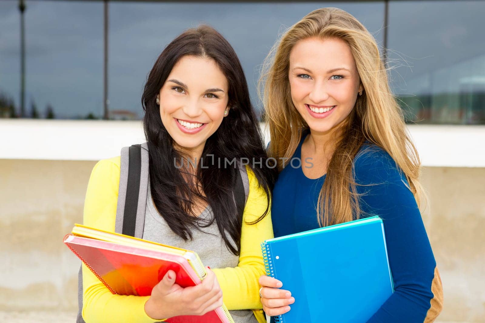 Two happy and beautiful teenage students in the school