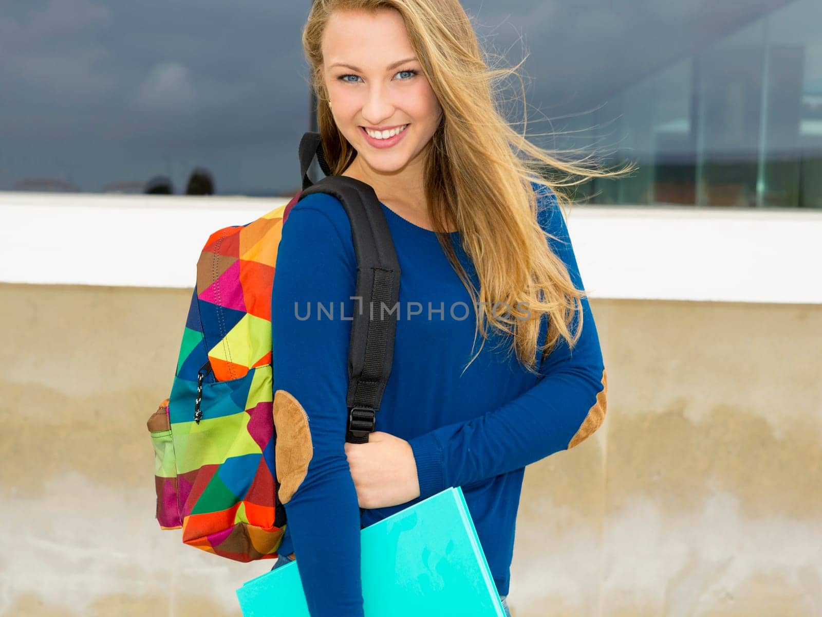 A beautiful student in the college holding a backpak and notebooks