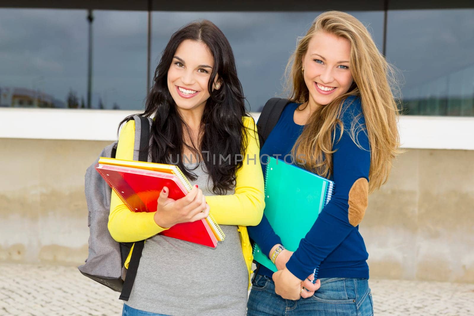 Two happy and beautiful teenage students in the school