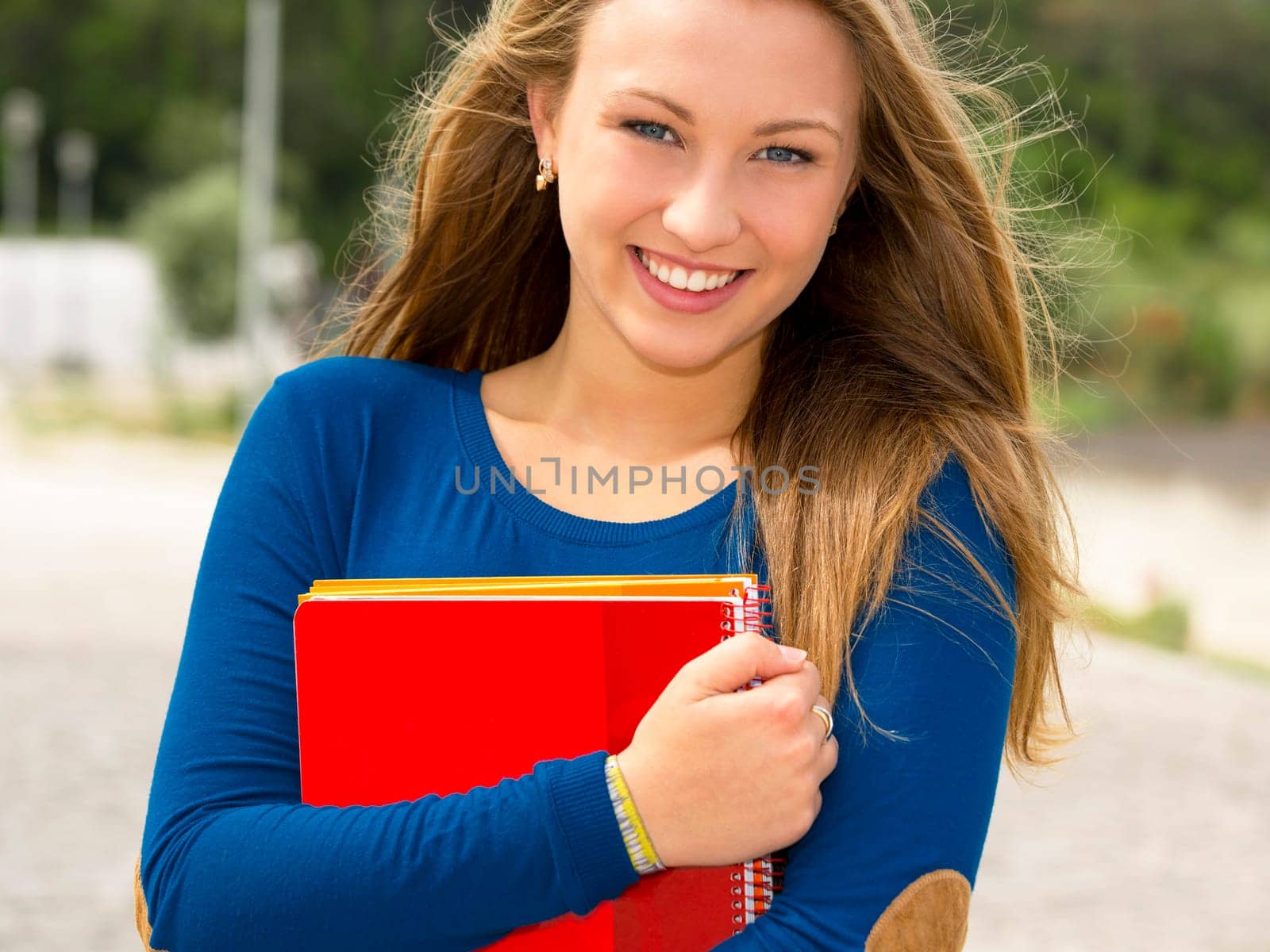 A beautiful student in the college holding a backpak and notebooks
