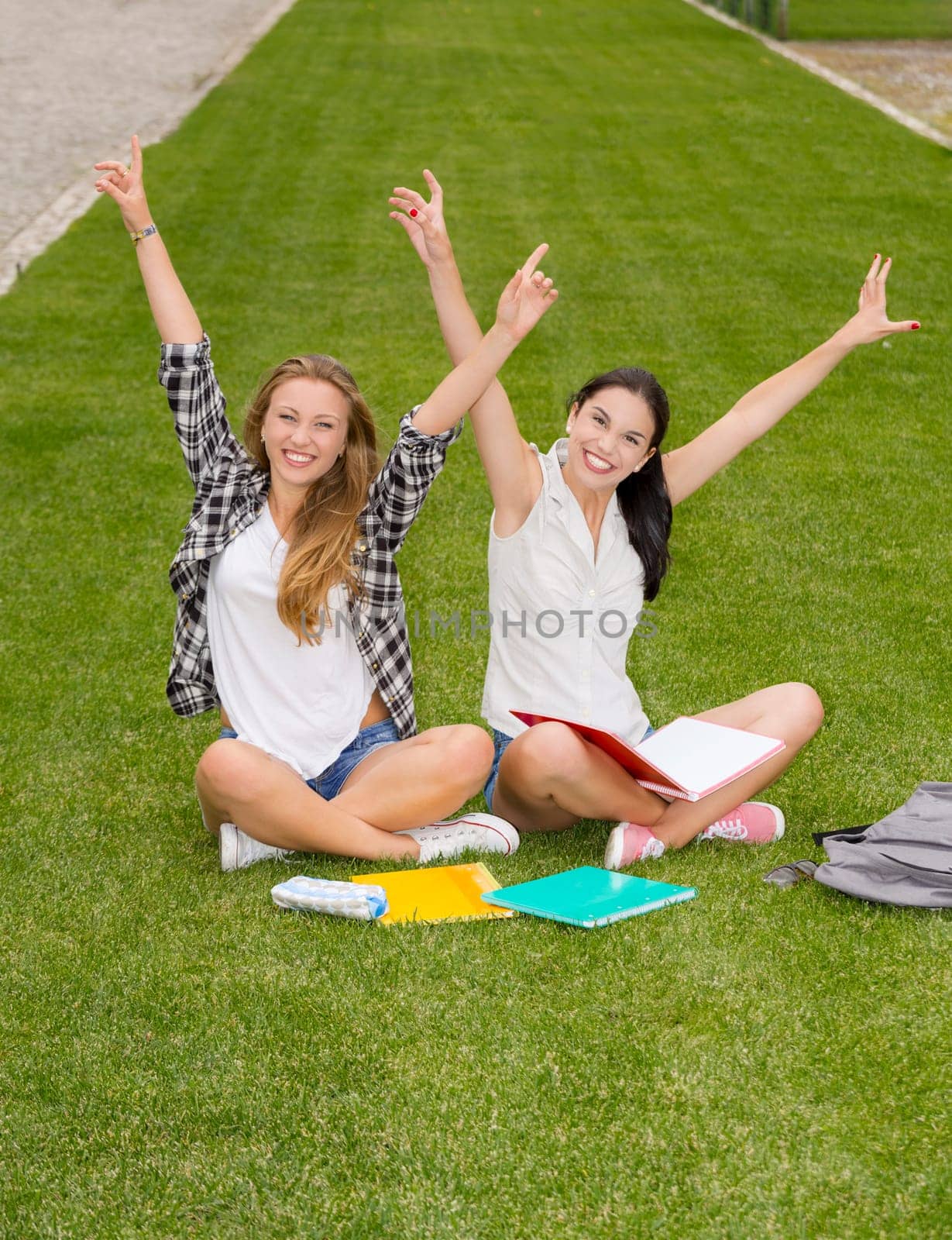 Happy best friends sitting on the grass and having a good time