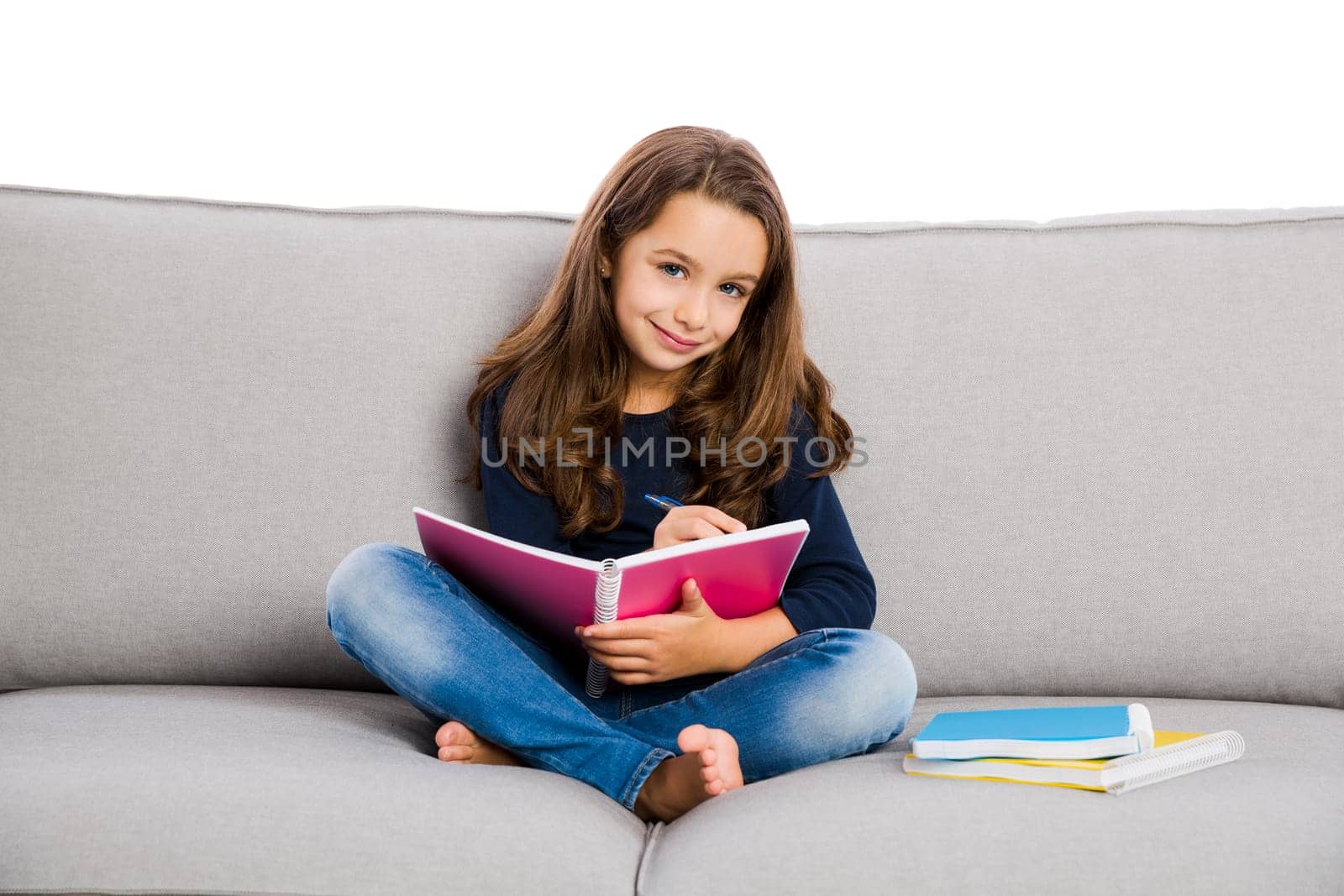 Little girl sitting on a couch and studying