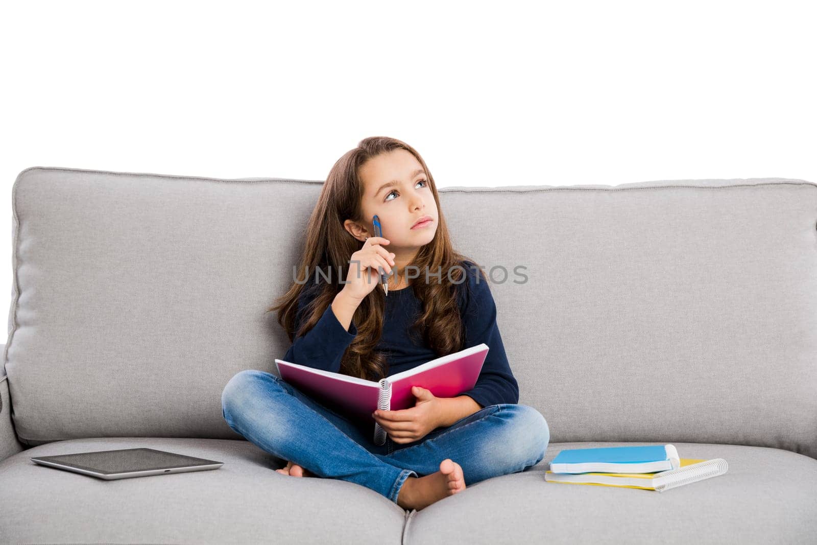 Little girl sitting on a couch and studying