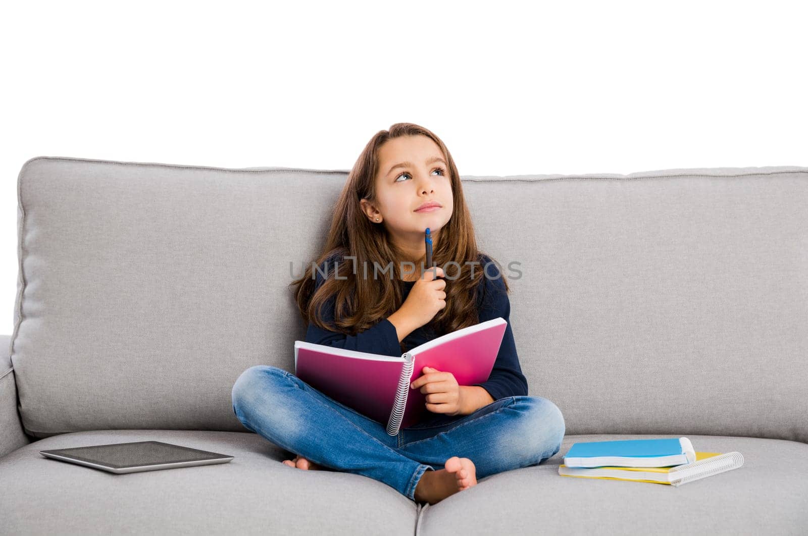 Little girl sitting on a couch and studying