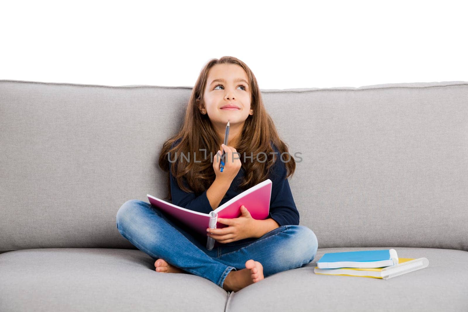 Little girl sitting on a couch and studying