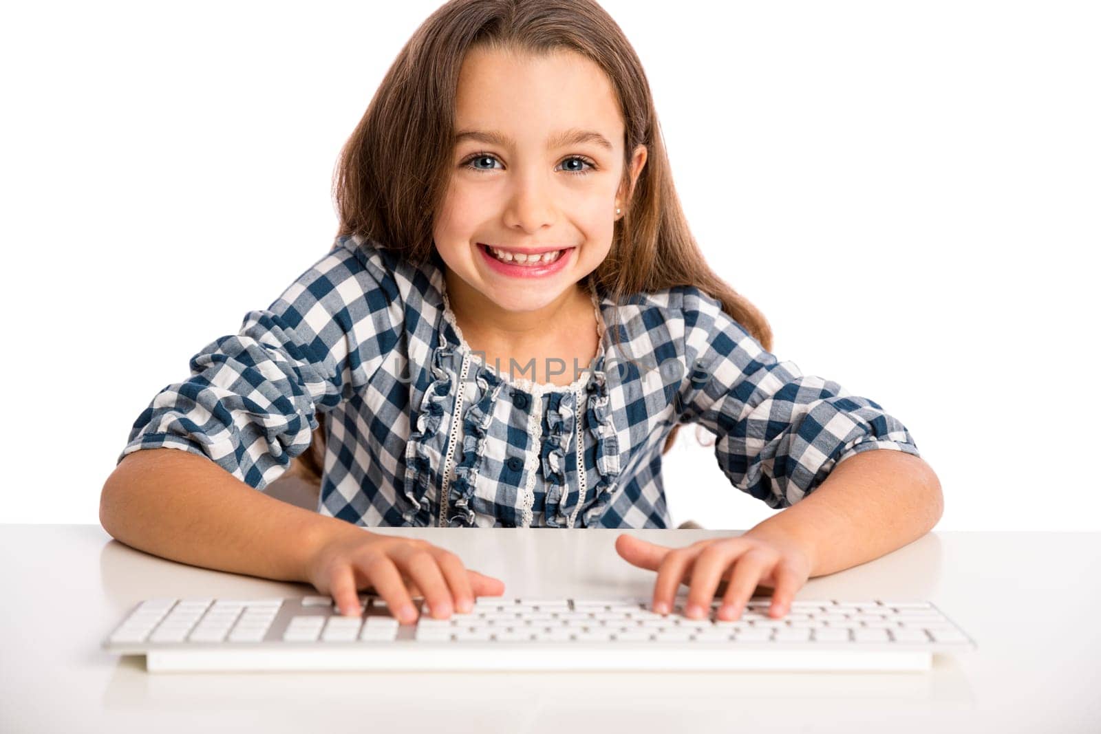 Little girl sitting on a desk and working with a computer