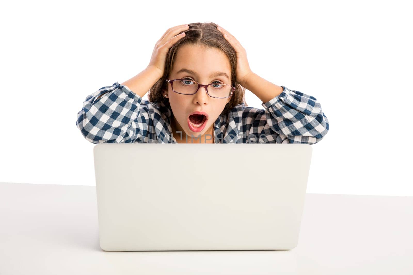 Little girl sitting on a desk and working with a laptop