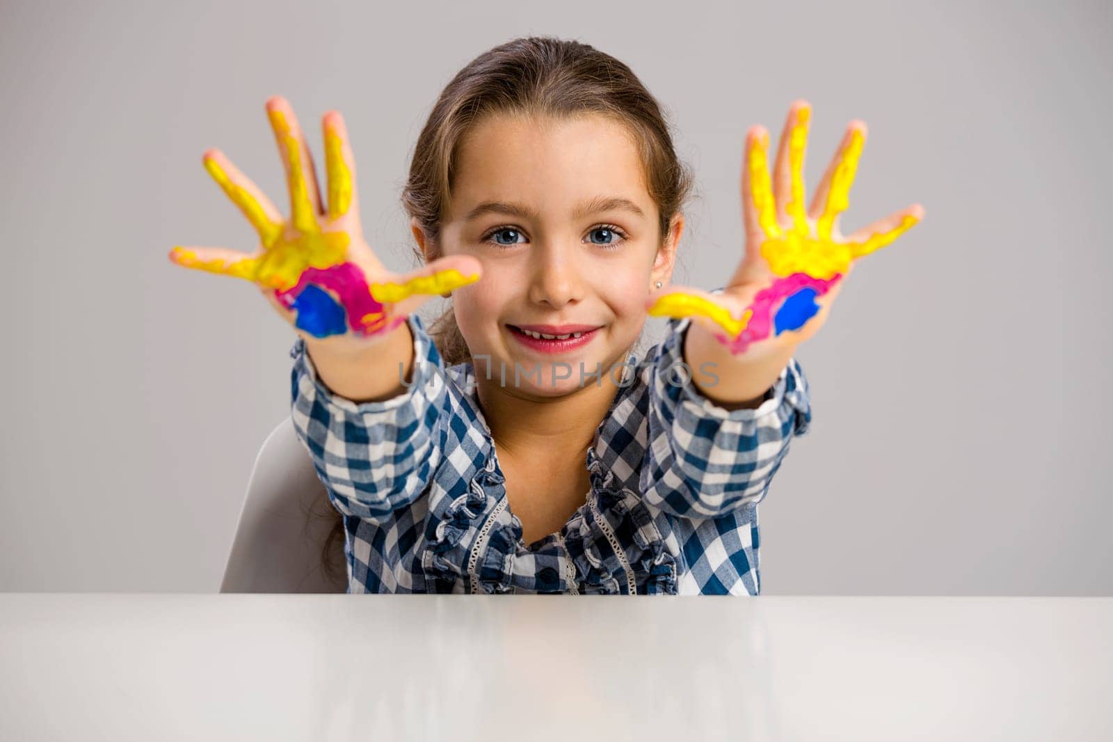 Cute smiling little girl with hands in paint