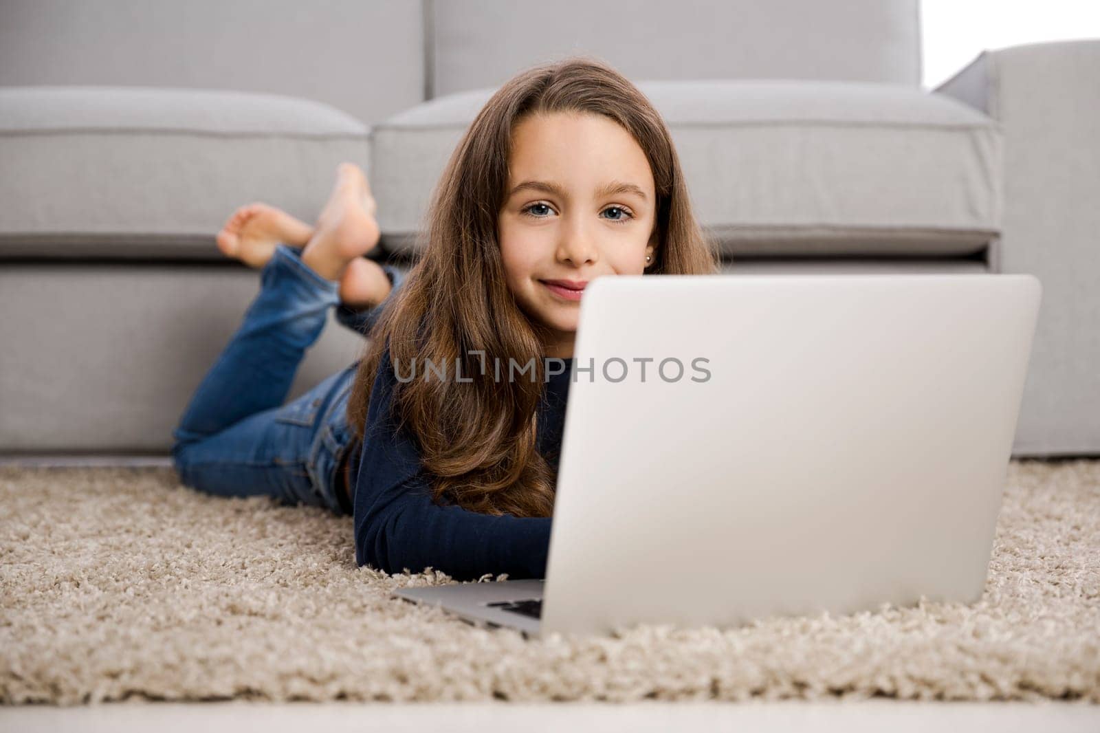 Happy little girl at home working with a laptop