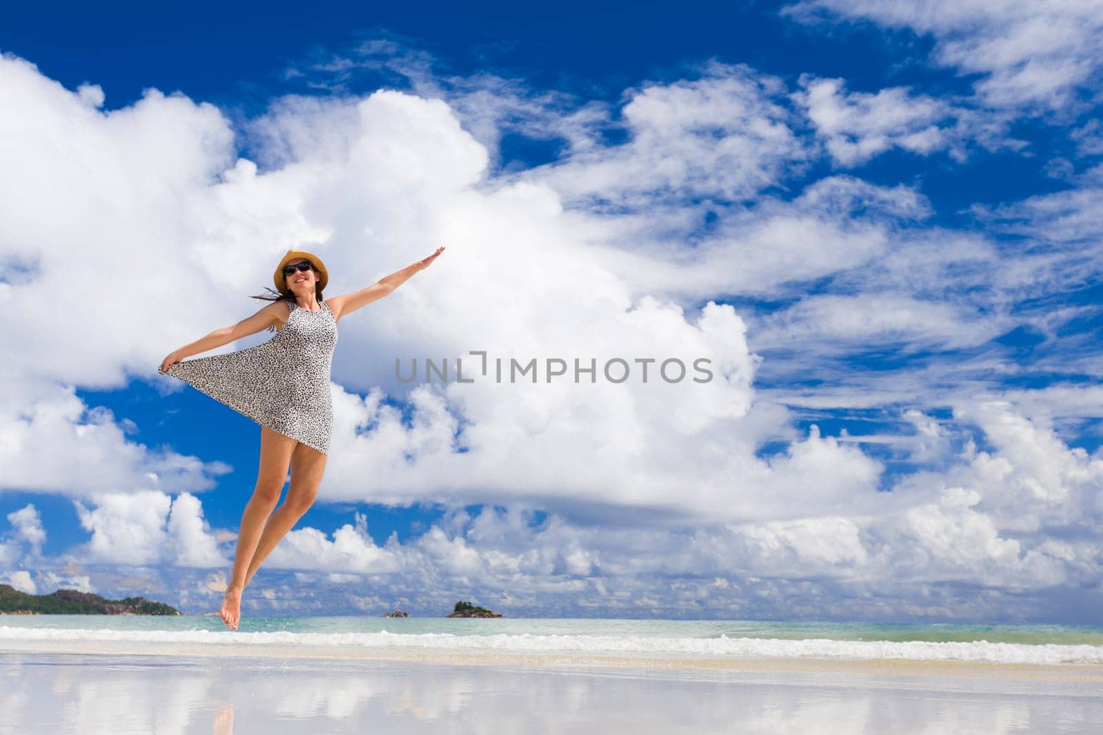 Beautiful woman jumping on the wonderful beach of Praslin, Seychelles