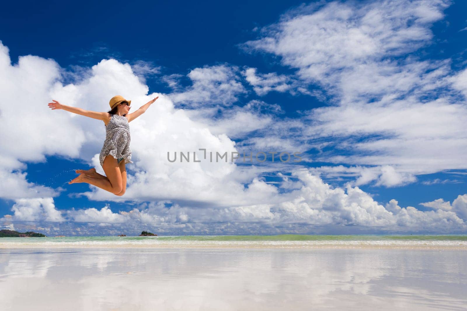Beautiful woman jumping on the wonderful beach of Praslin, Seychelles