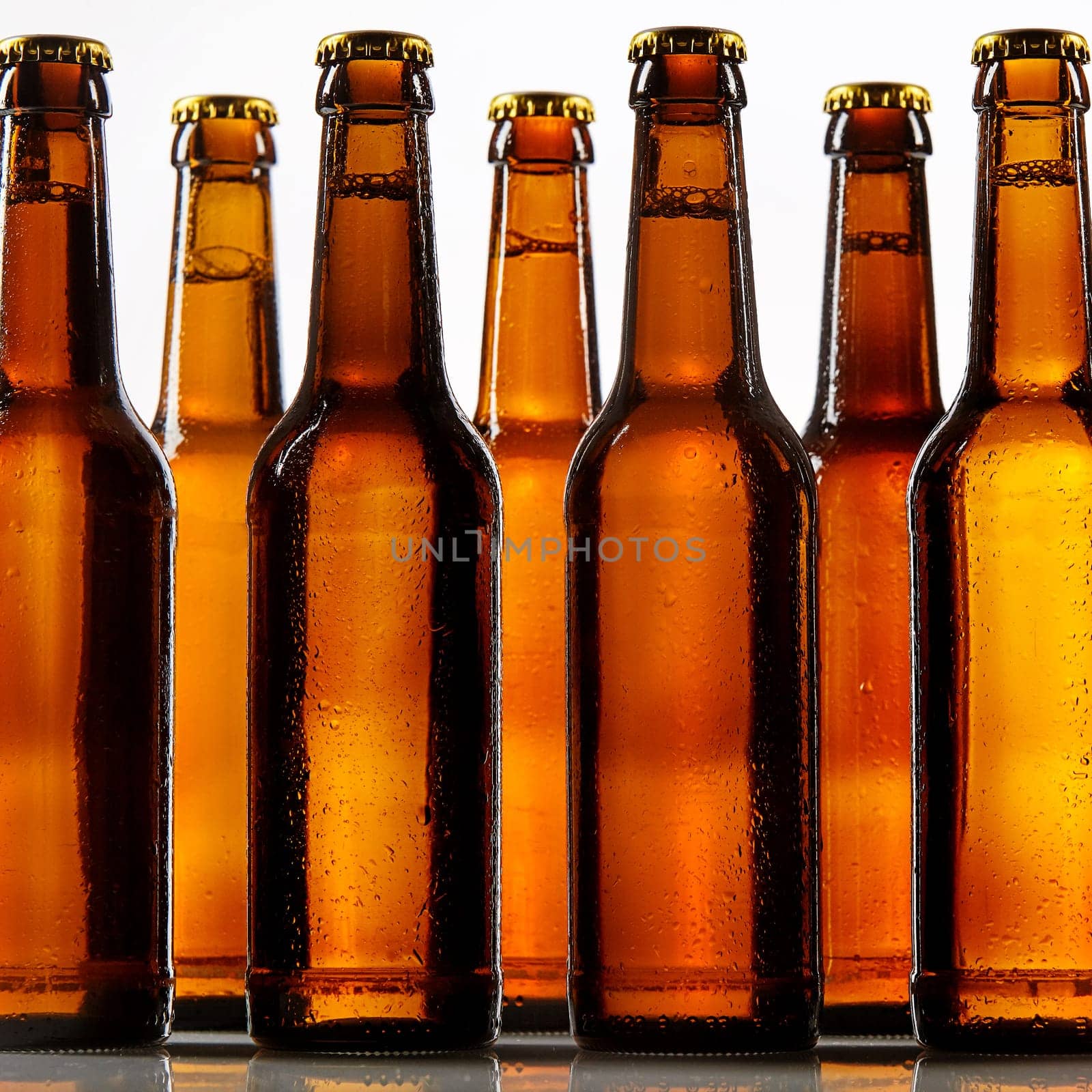 Close up view of tall beer bottles with metal caps and condensation covering each one