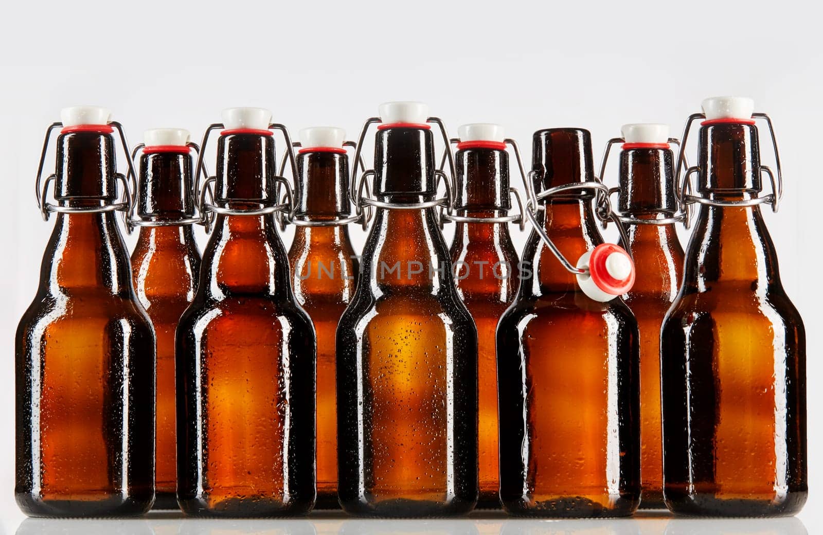Beer packaged in clear brown unlabeled bottles two rows deep with stopper top and metal brace