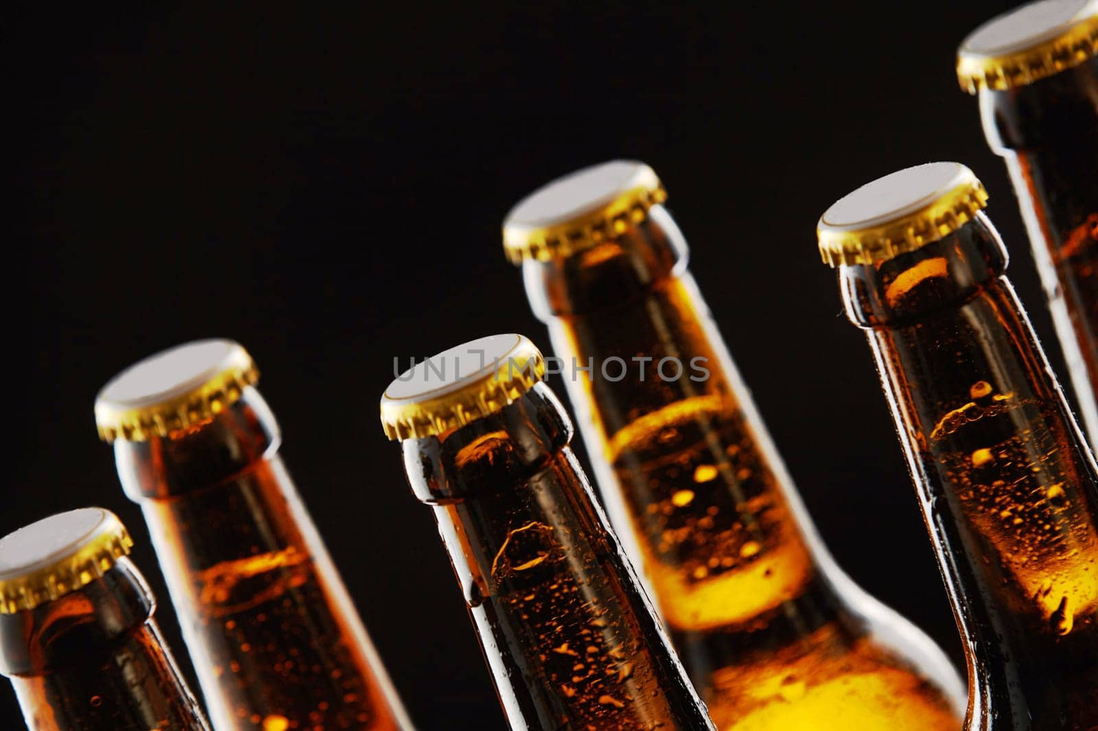 Necks of sealed beer bottles with condensation in a close up view over a black background in a tilted angle view conceptual of Oktoberfest