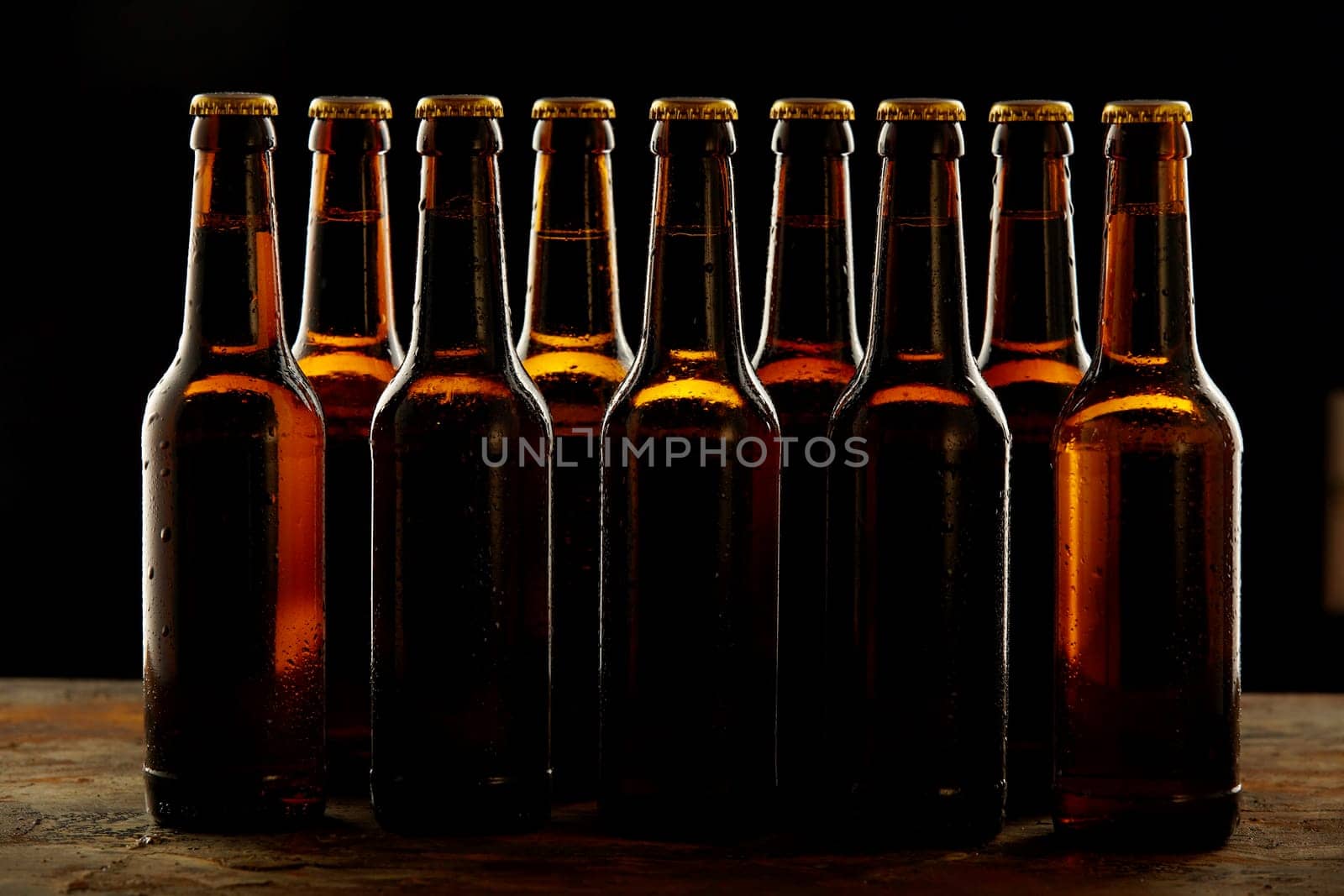 Group of sealed unlabelled brown beer bottles standing on a wooden counter in a concept of the Oktoberfest or for branding and advertising