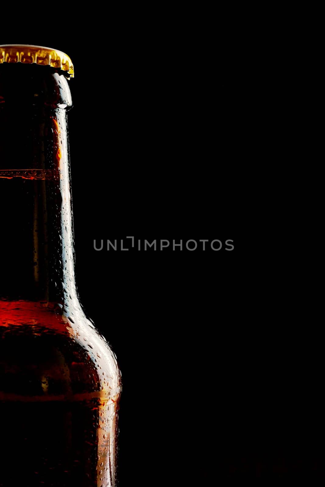 Single partial unlabelled ice cold beer bottle as a border over a black background with copy space for Oktoberfest