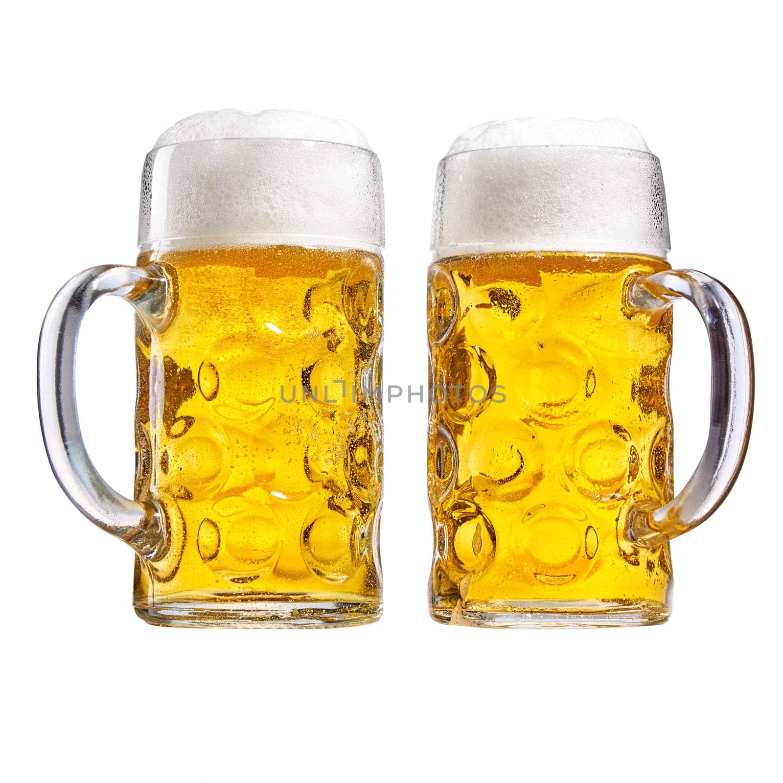 Two glass tankards of chilled beer with a good frothy head side by side with the handles in opposite directions isolated on white conceptual of the Oktoberfest