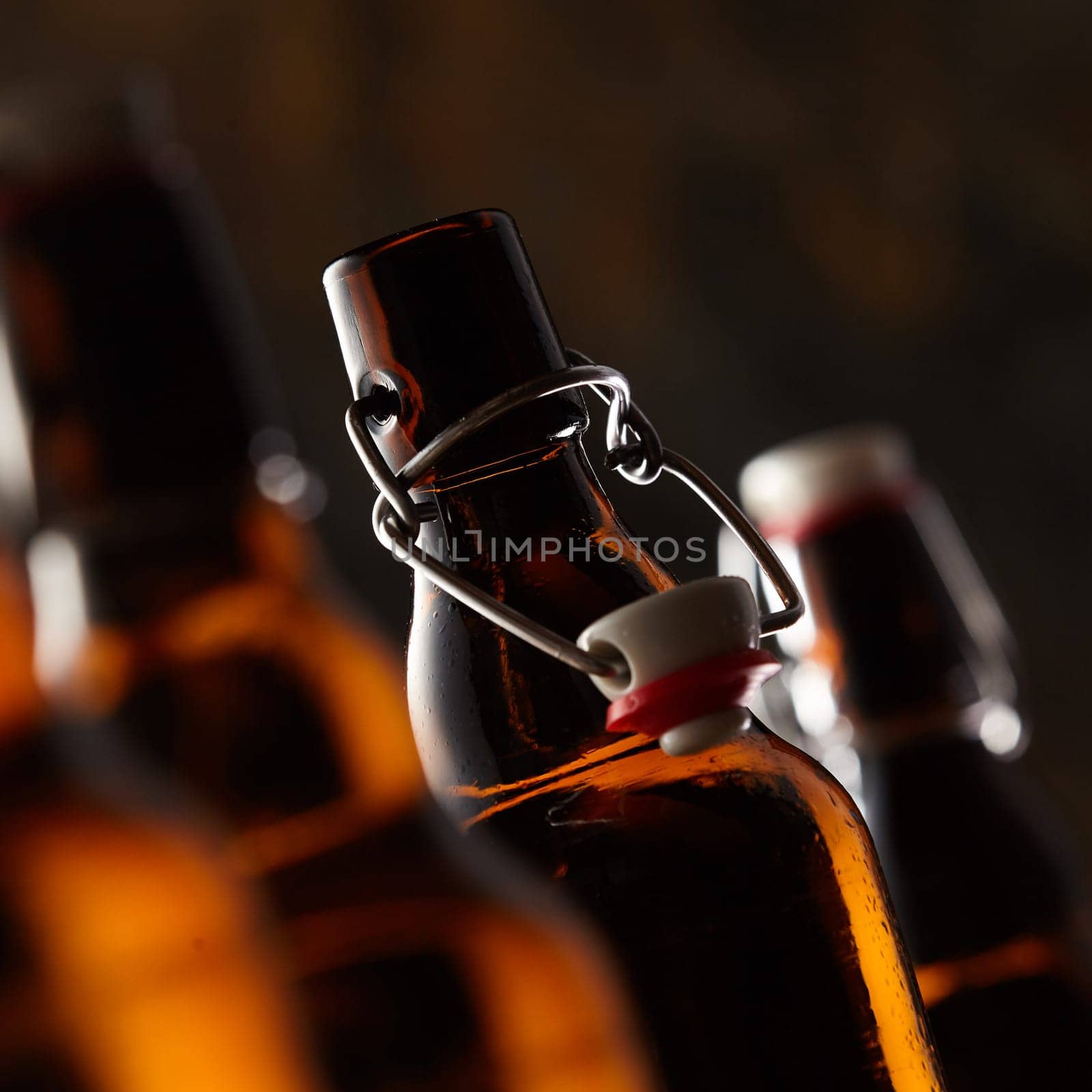 Open bottle of beer with stopper in a close up selective focus tilted view in square format in a dark environment conceptual of Oktoberfest