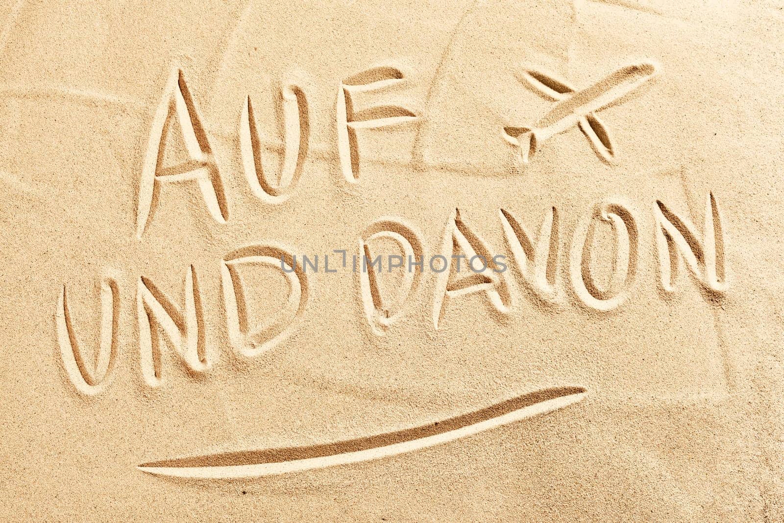 Auf und Davon German text with sketched airplane on tropical beach sand conceptual or spring or summer vacations and flying by air to your holiday destination