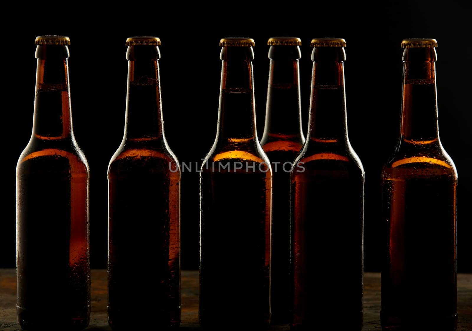 Branding and marketing concept for beer with a line of unopened unlabelled full blank brown bottles on a dark shadowy background conceptual of Oktoberfest or nightlife