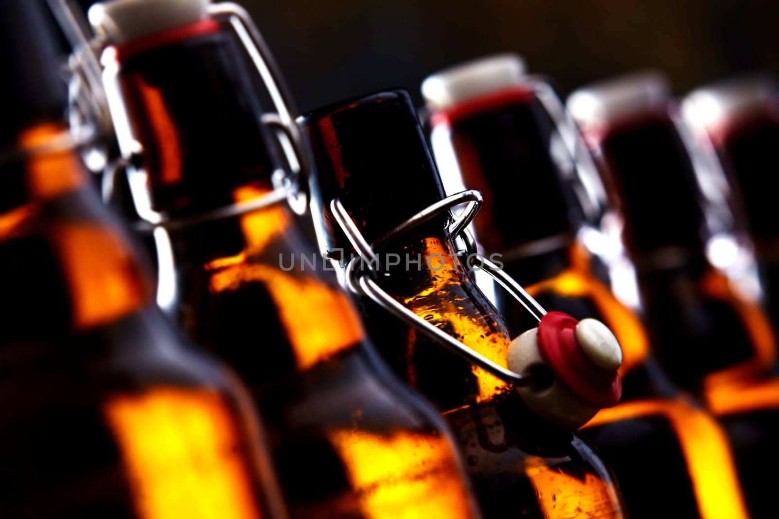 Row of beer bottles with stoppers glowing in the dark with selective focus to the stopper of an open bottle